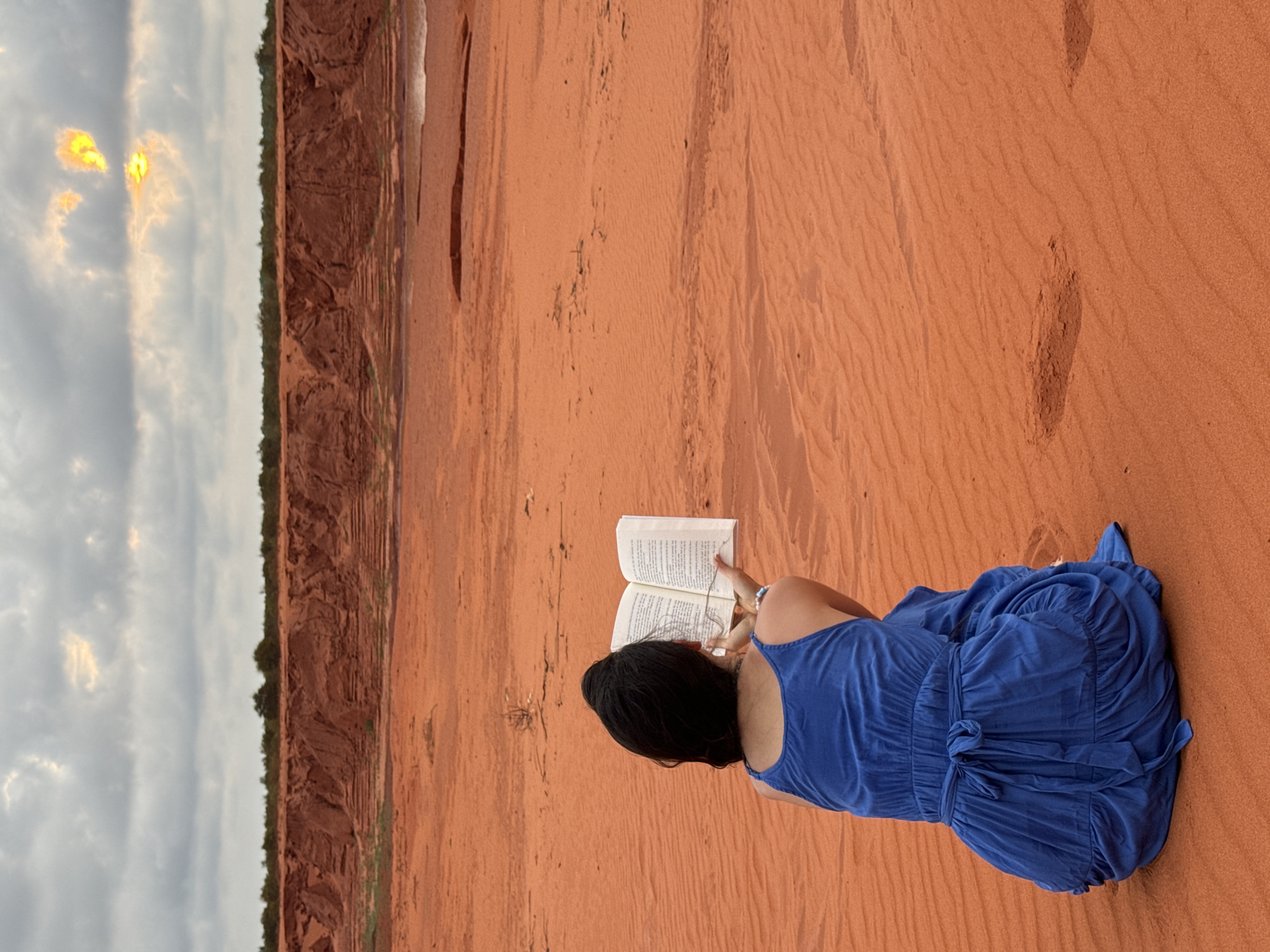 Woman reads book on red sand dunes in Vietnam