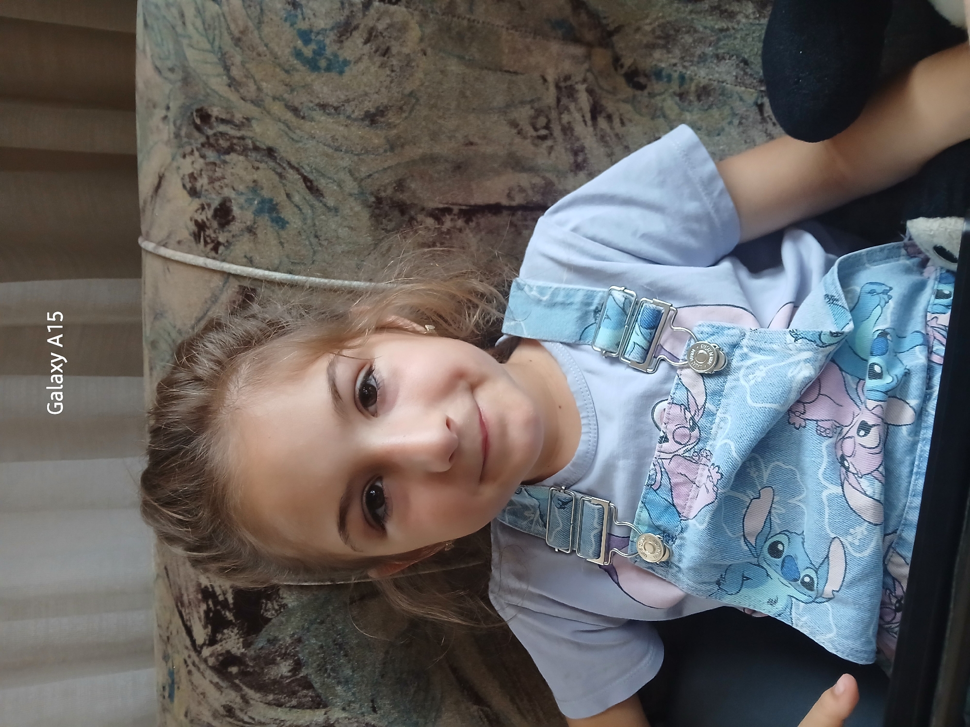 Young girl photographed on patterned sofa in Bulgarian village