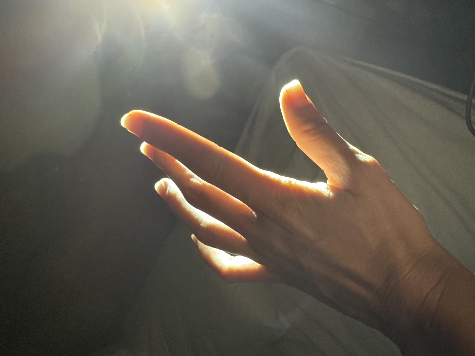 Hand reaches toward sunlight in Indonesian bedroom