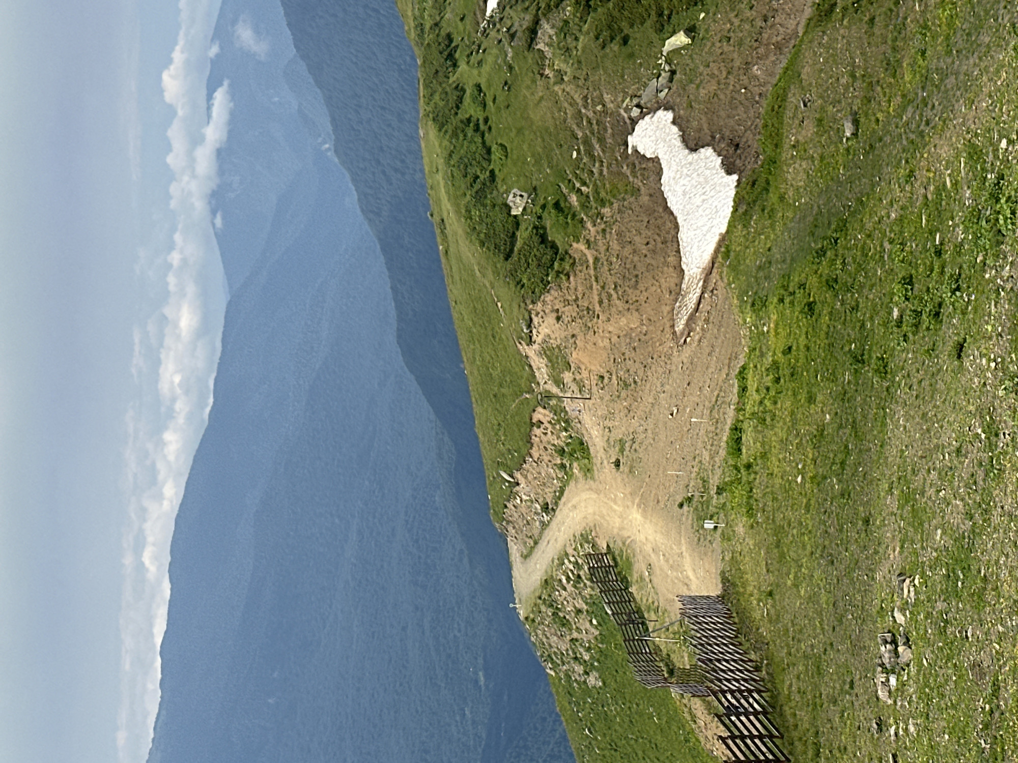 Alpine mountain terrain with trails, snow patches, and ski infrastructure