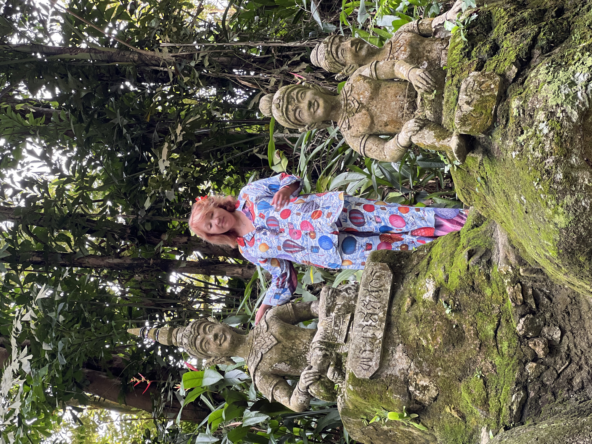 Tourist explores weathered stone musician statues in Ko Samui jungle