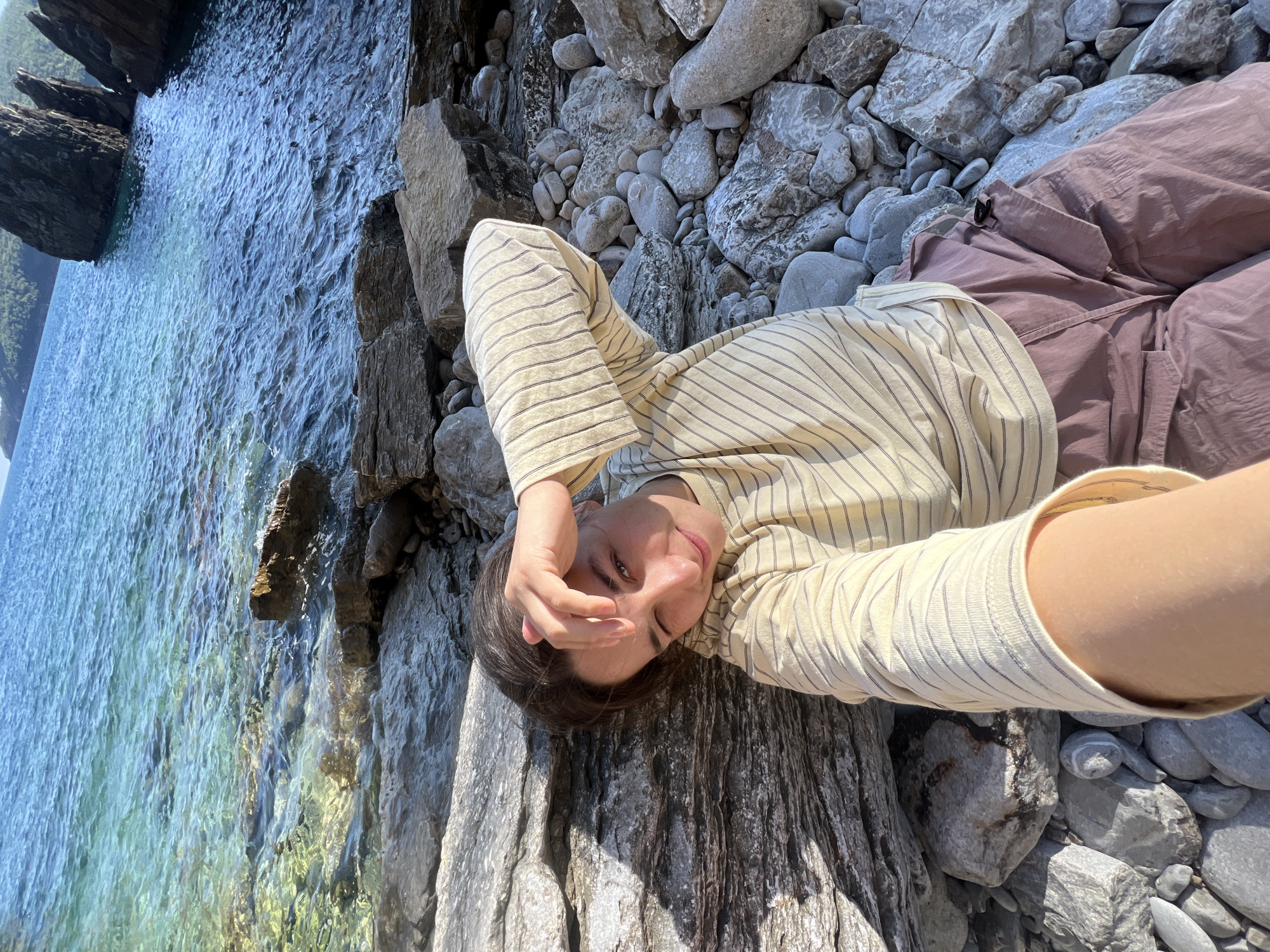 Woman rests on waterside rock in Montenegro