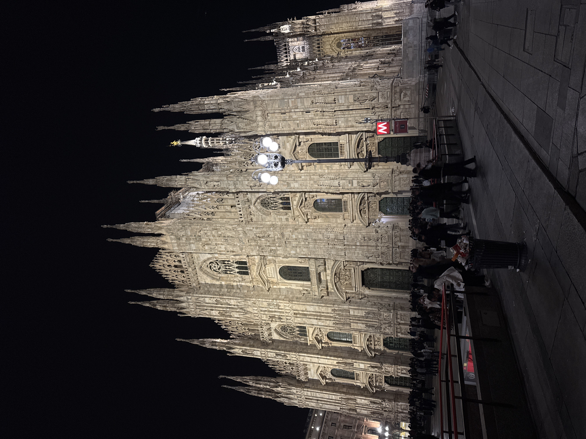 Evening tourists photograph illuminated Milan Cathedral and landmarks