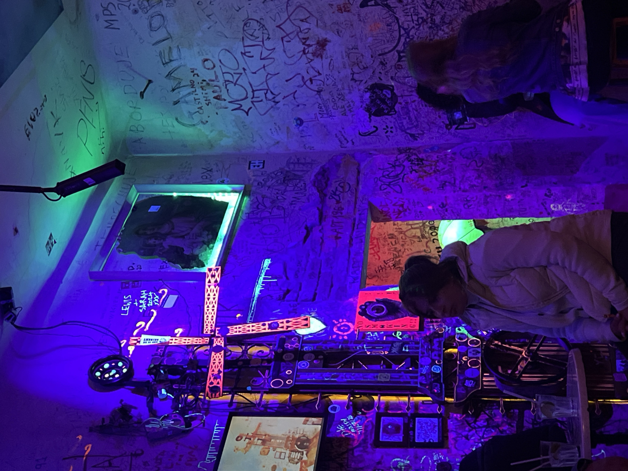 Woman walks through neon-lit graffiti bar in Budapest