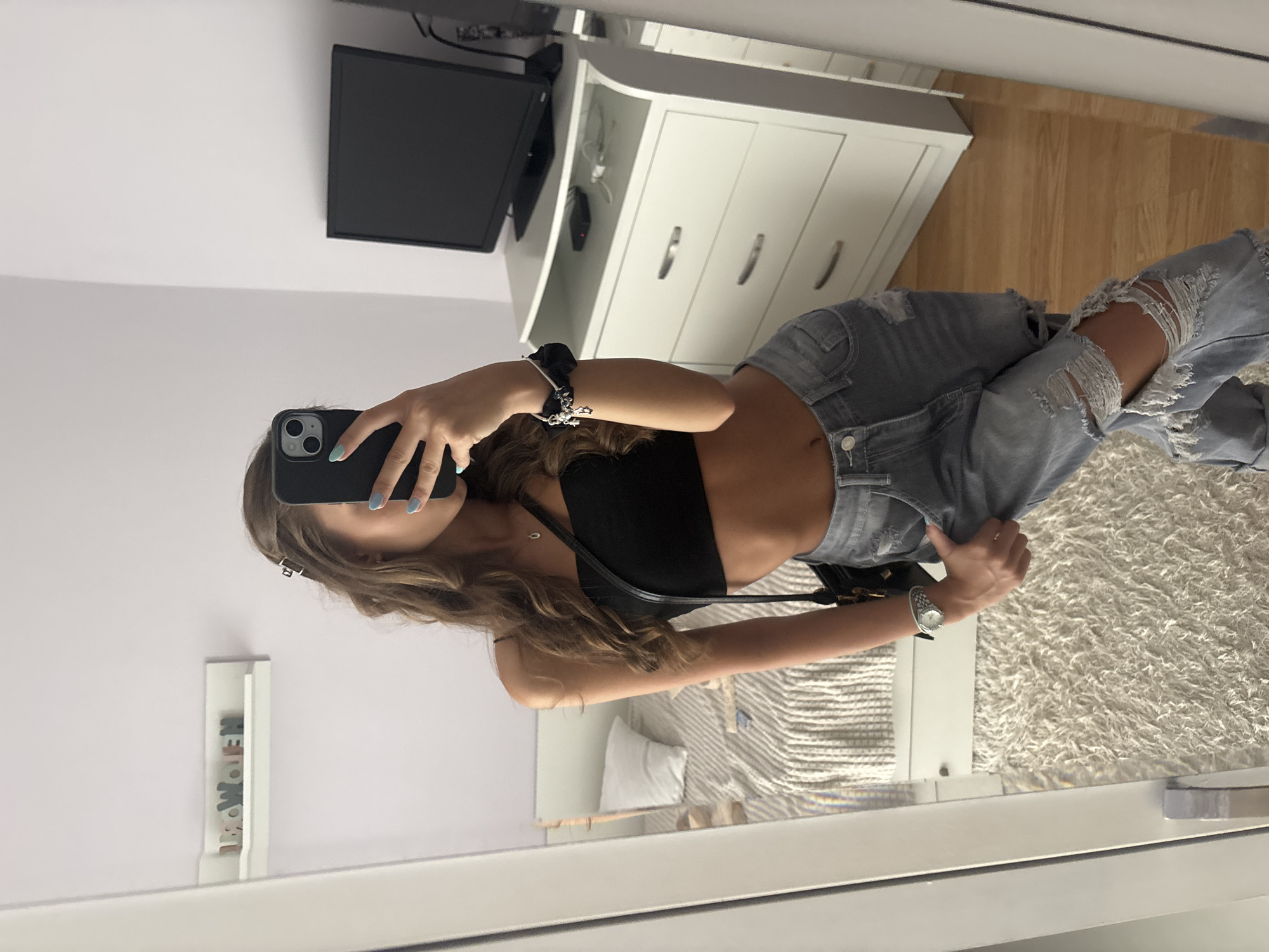 Mirror selfie in crop top and ripped jeans.