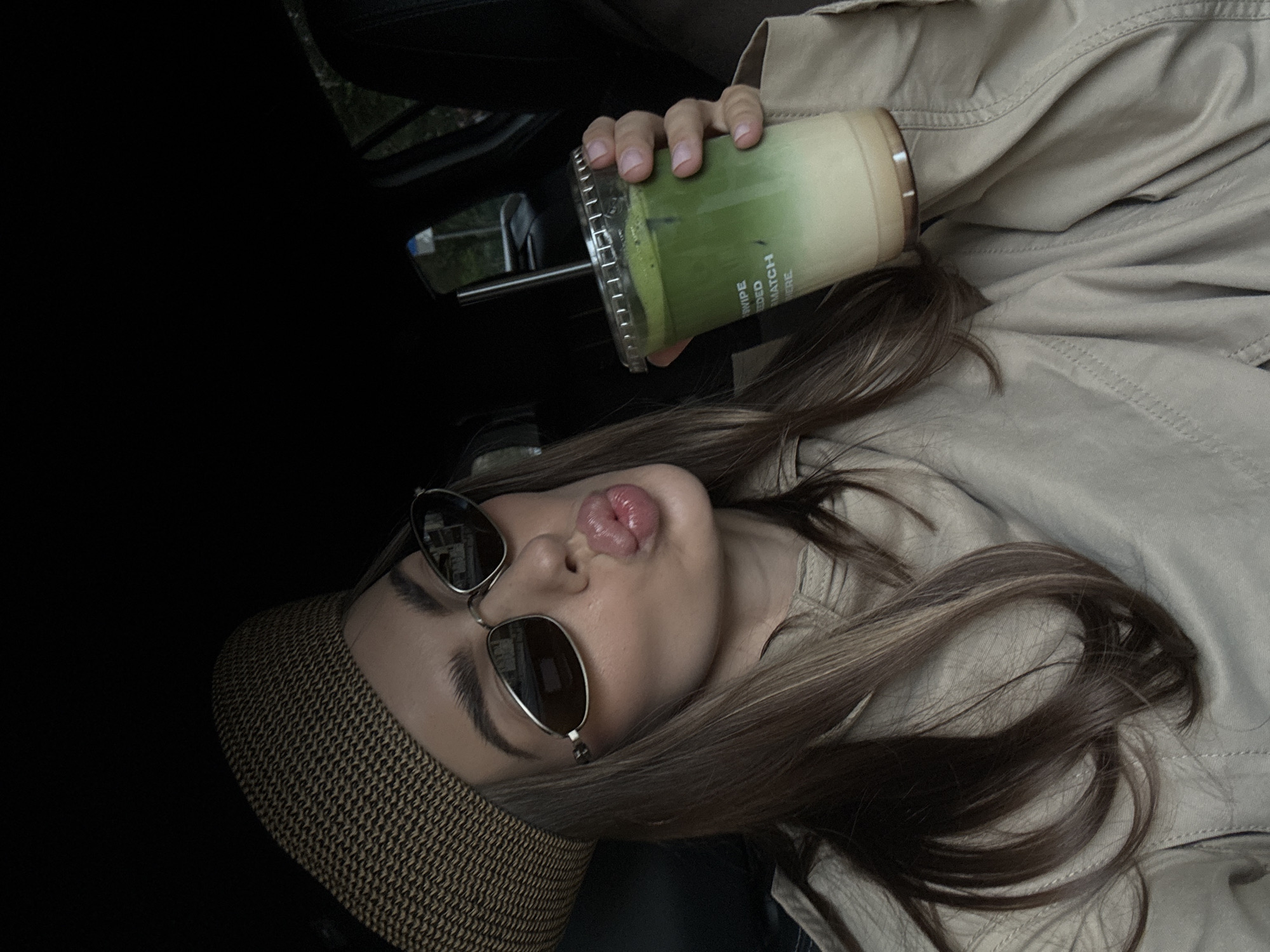 Woman poses with matcha drinks in parked car in Warsaw