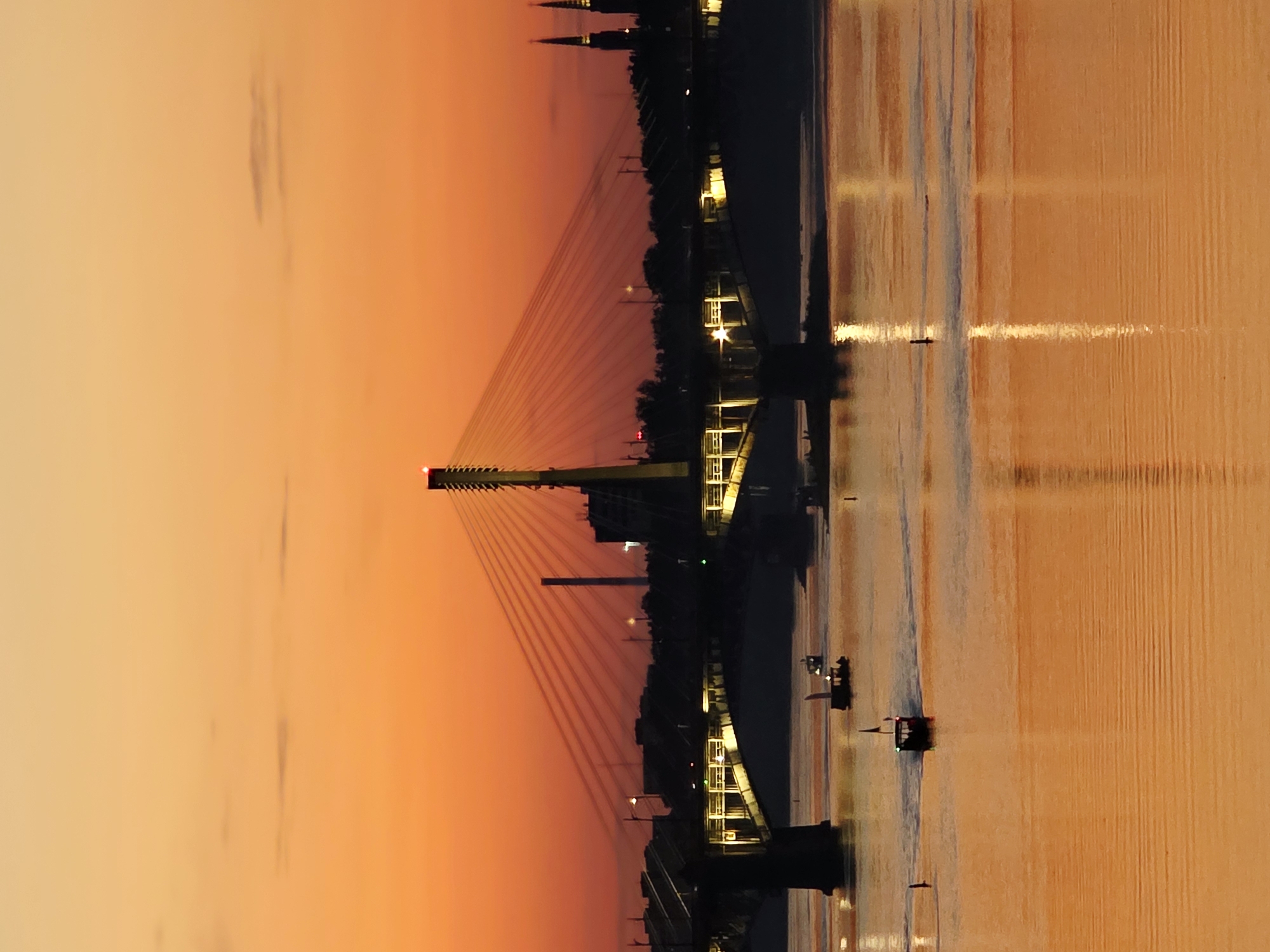 Warsaw's Vistula riverfront at golden hour, bridges and stadium lit up