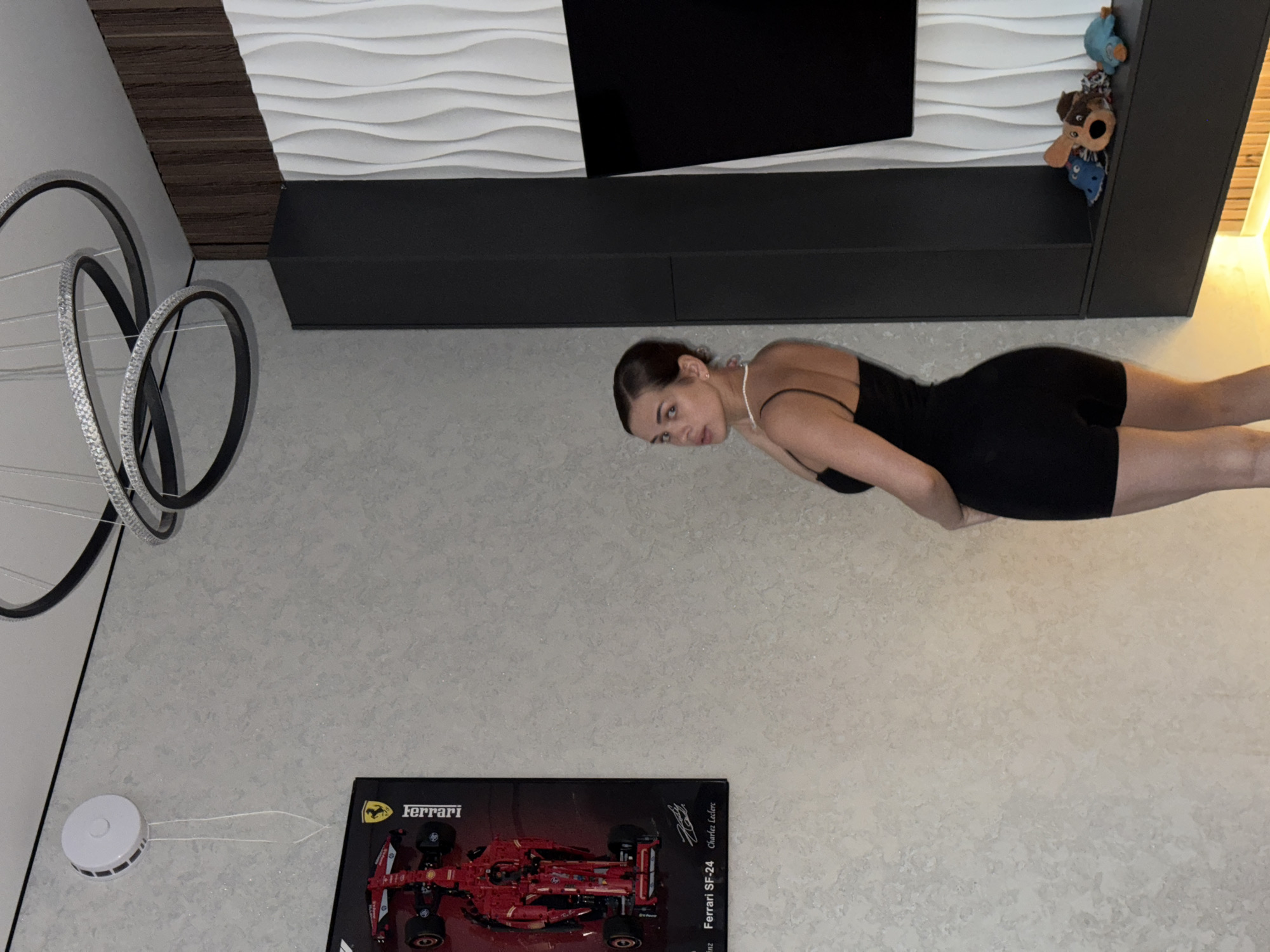 Woman poses with cat in Russian home featuring Ferrari poster
