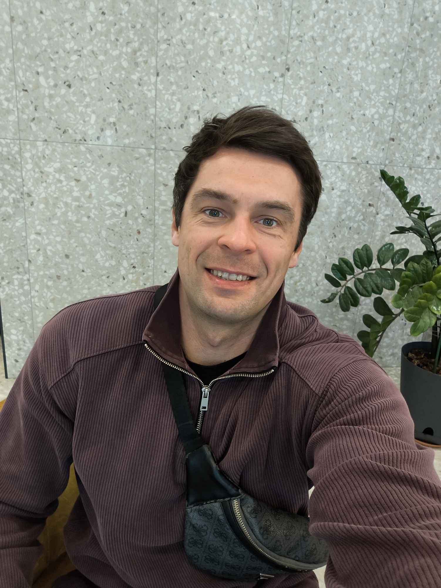 Smiling man in purple jacket observed indoors in Moscow