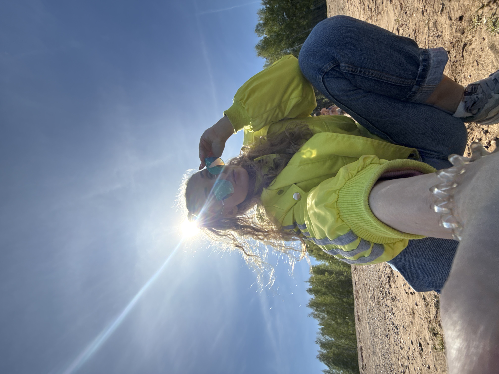 Young person sits in sunny sandy area in Chaikovsky