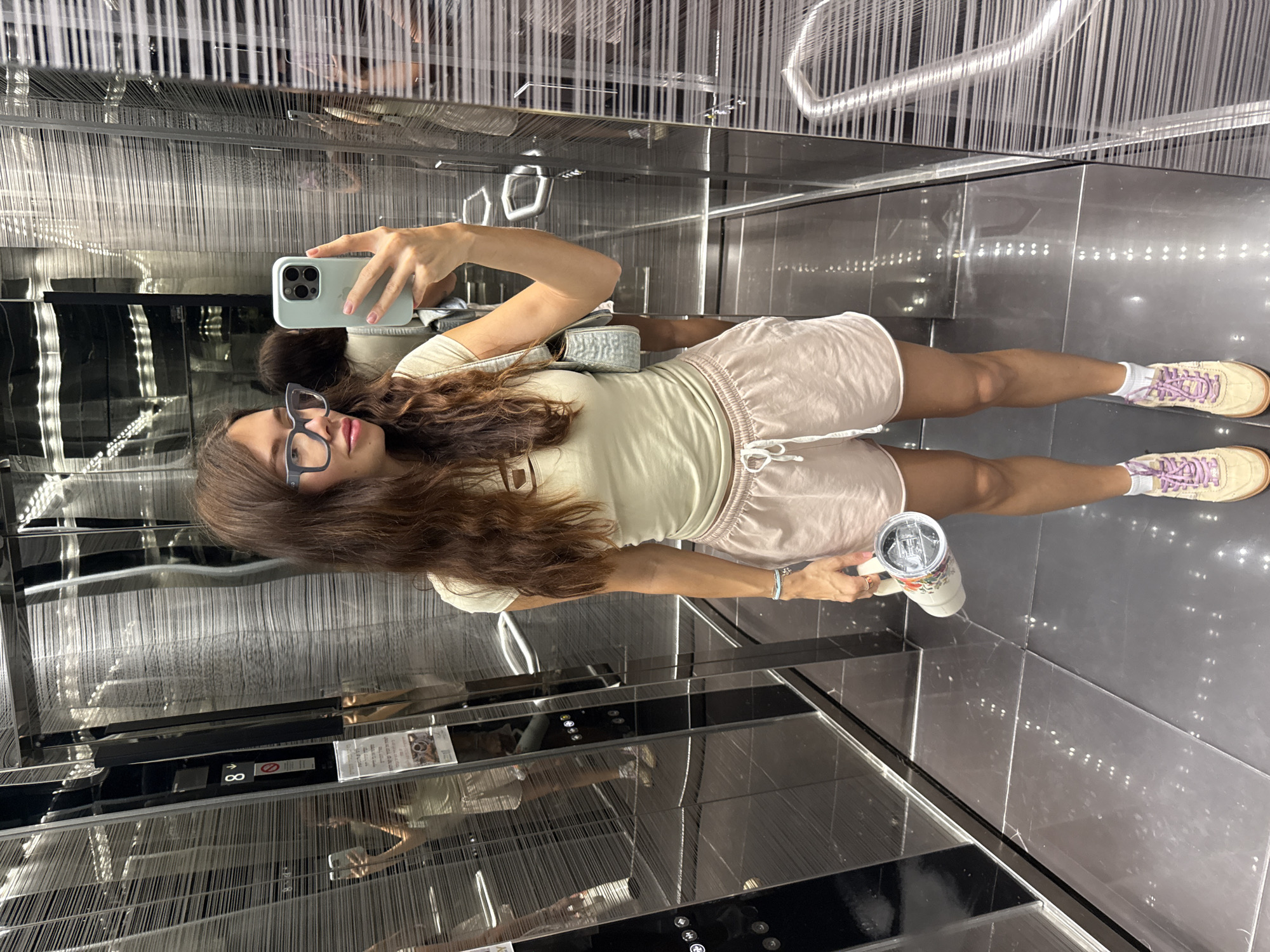 Woman takes elevator selfie while holding cup