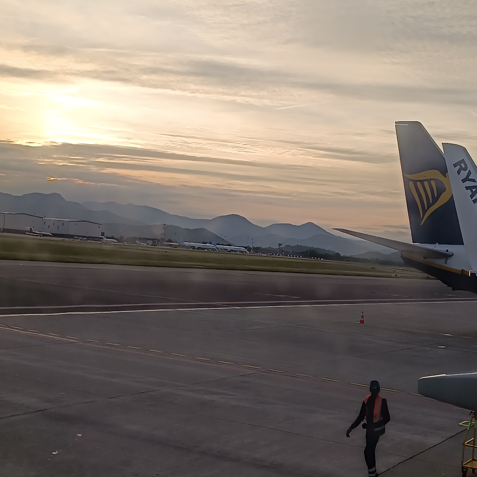 Airport dawn scene observed with warm lighting, layered clouds