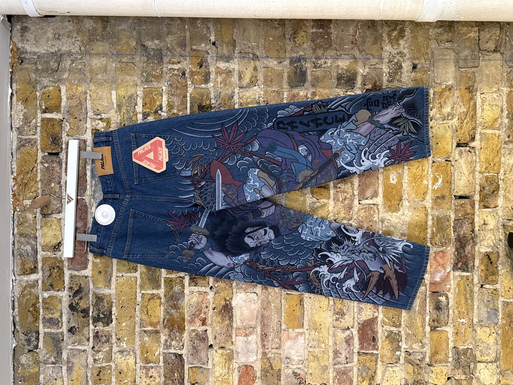 Japanese-decorated jeans displayed against brick wall in London
