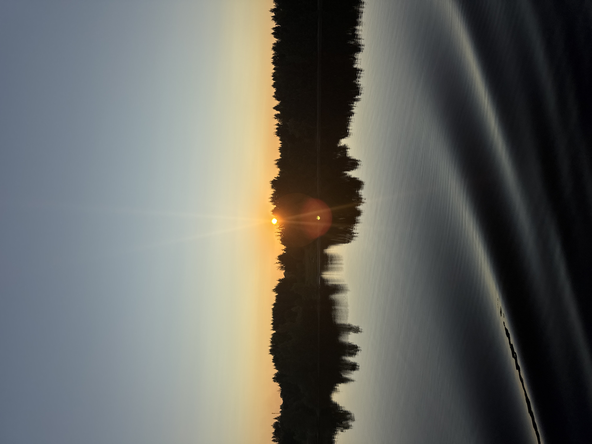 Sunset over calm Russian lake and river, viewed from shore and boat