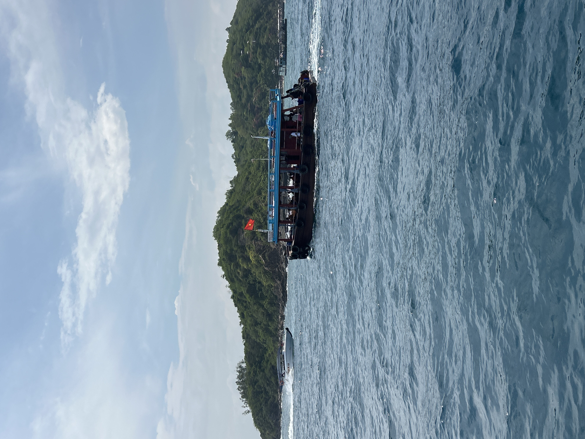 Wooden passenger boat navigates Nha Trang bay, Vietnamese flag flying