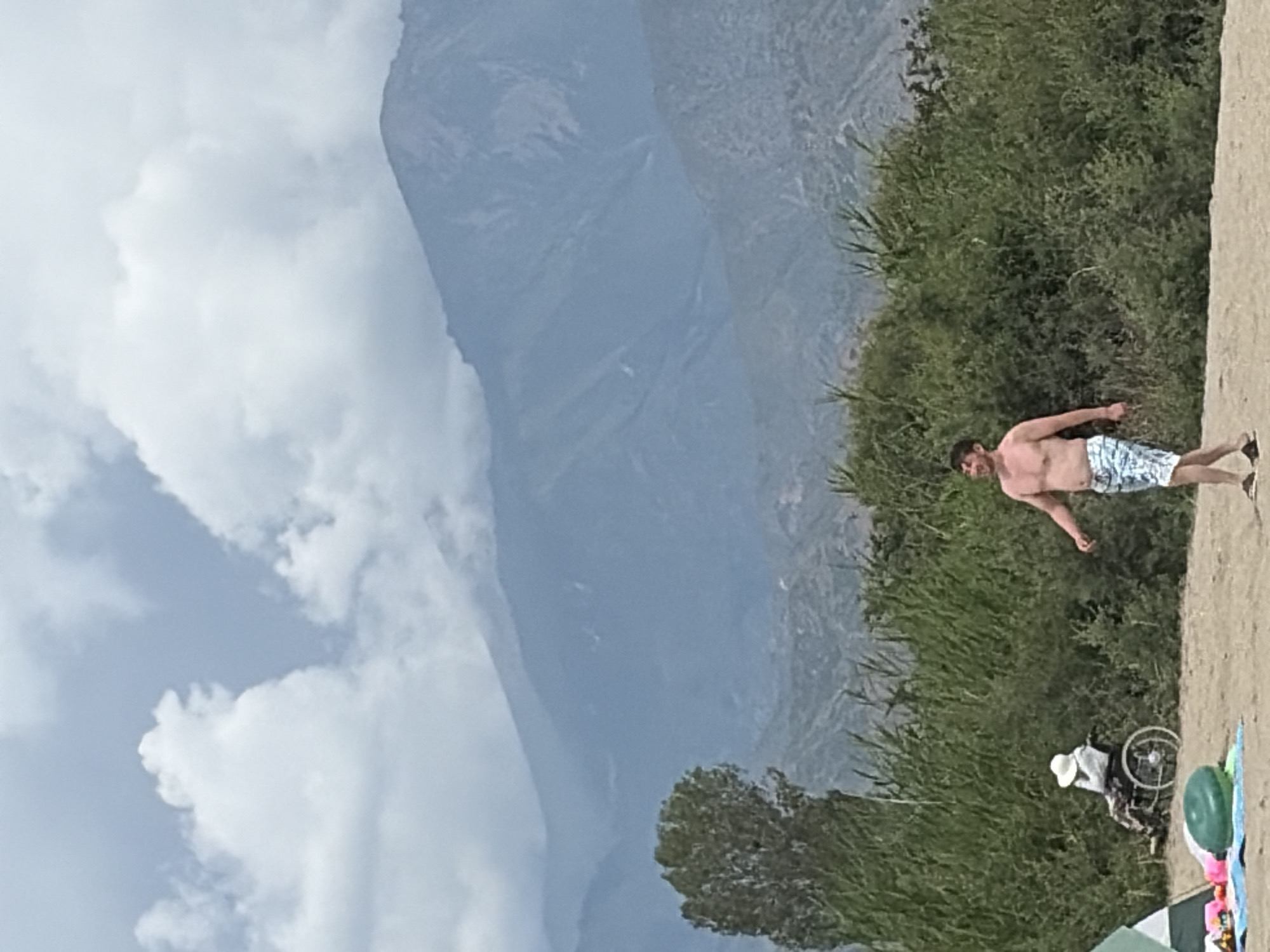 A cloudy day at a mountain-backed beach, full of activity.