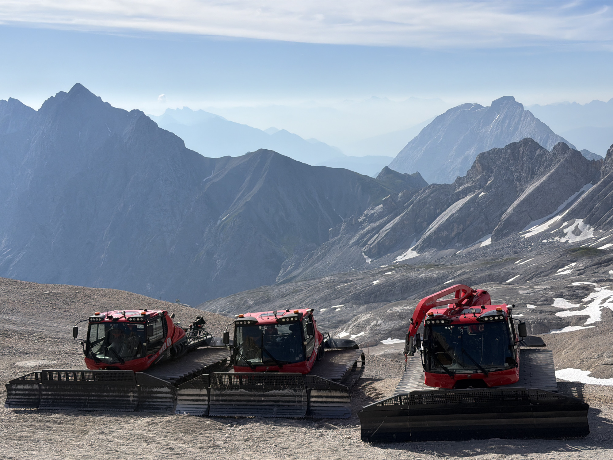 Three red snowcats parked on an Austrian mountain slope