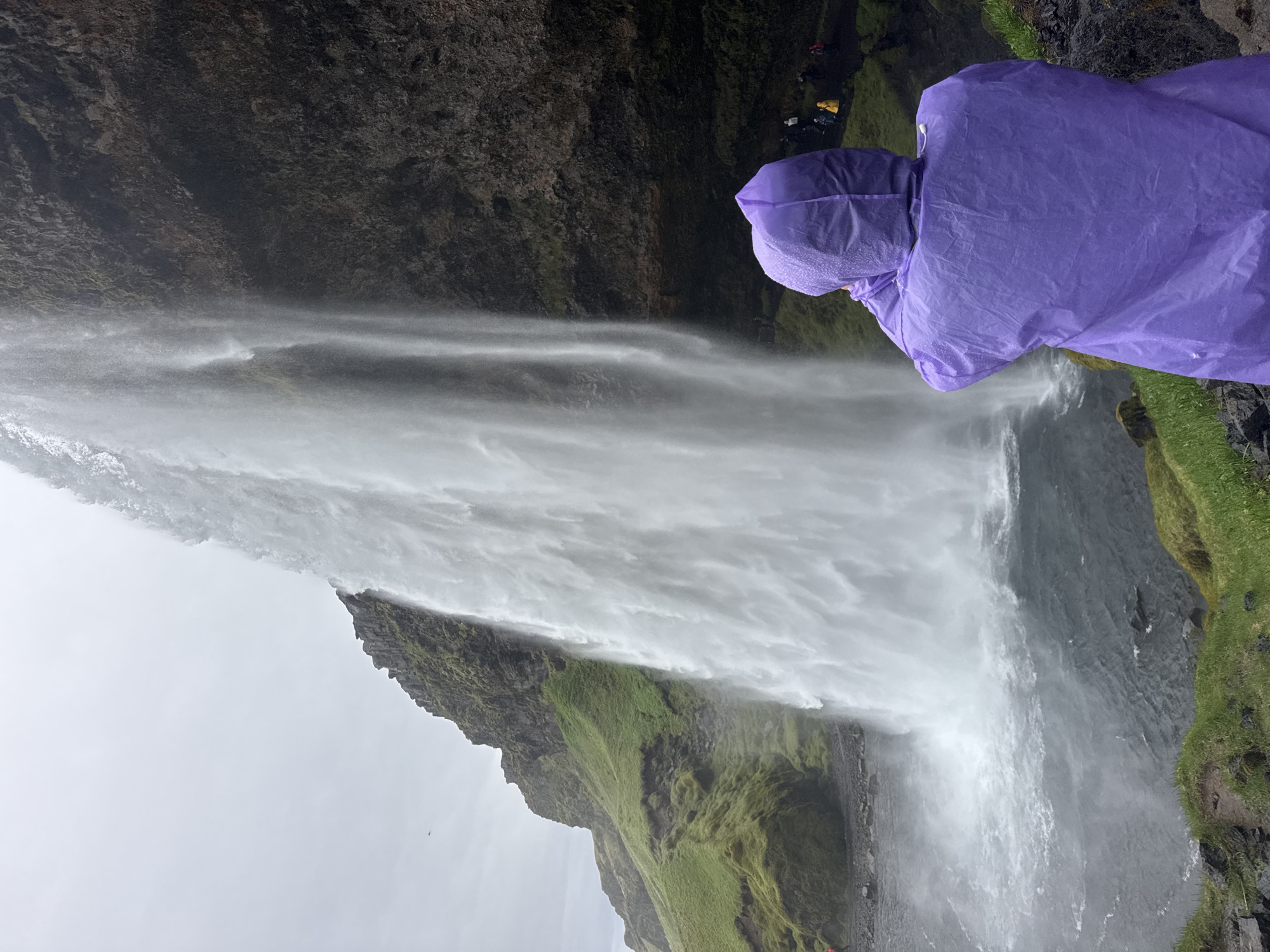 Tourists visit Seljalandsfoss waterfall on overcast Iceland morning