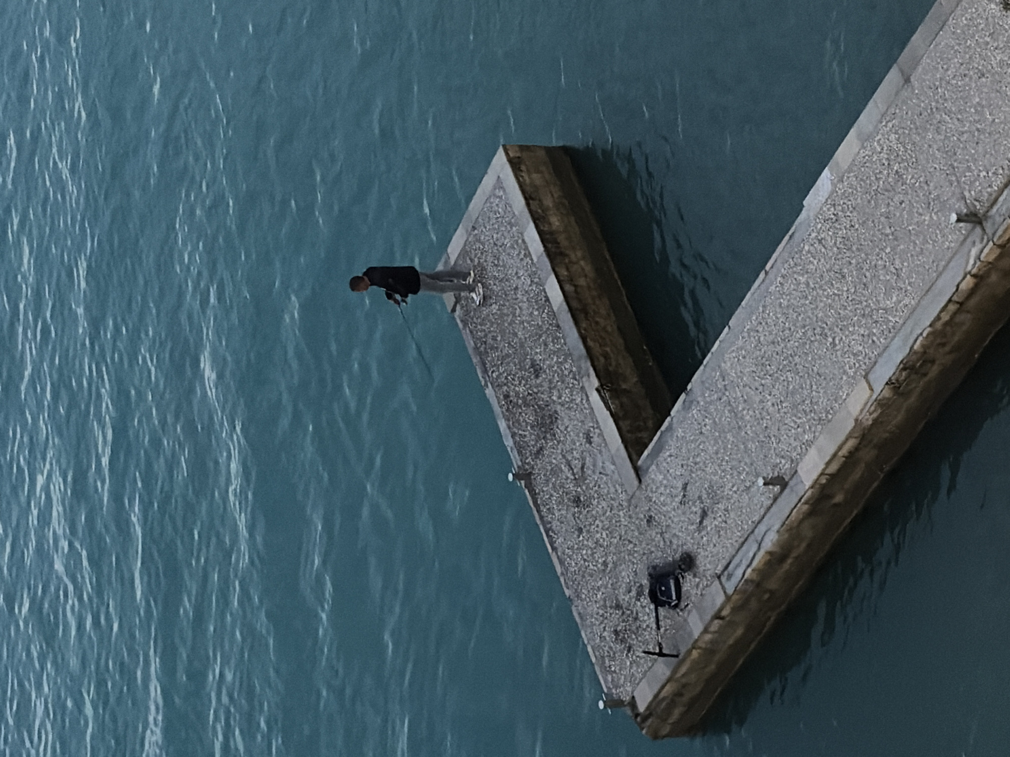 Solitary figure observed on Budva pier at dusk