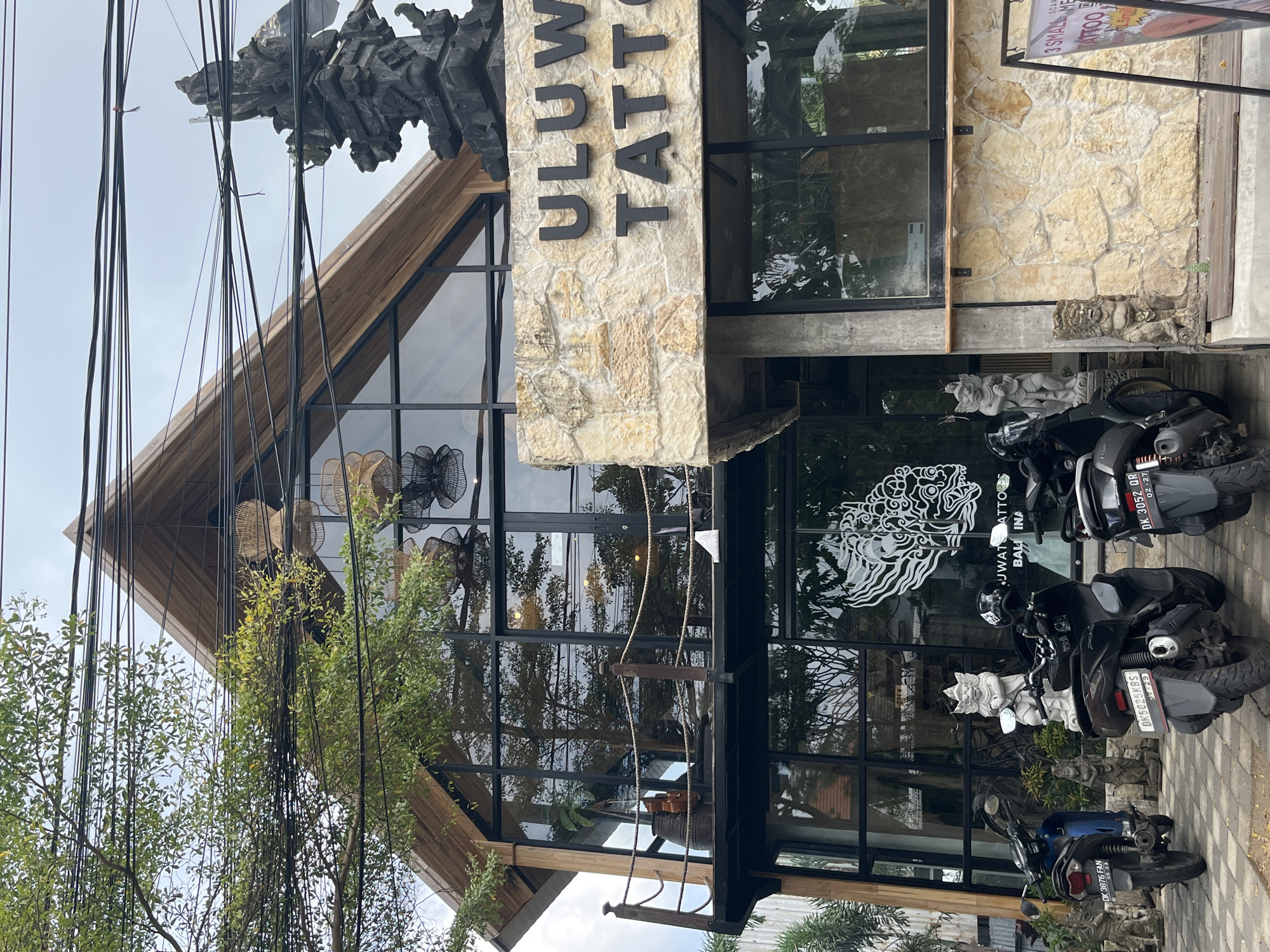 Tattoo parlor exterior and Balinese statuary documented in Kuta