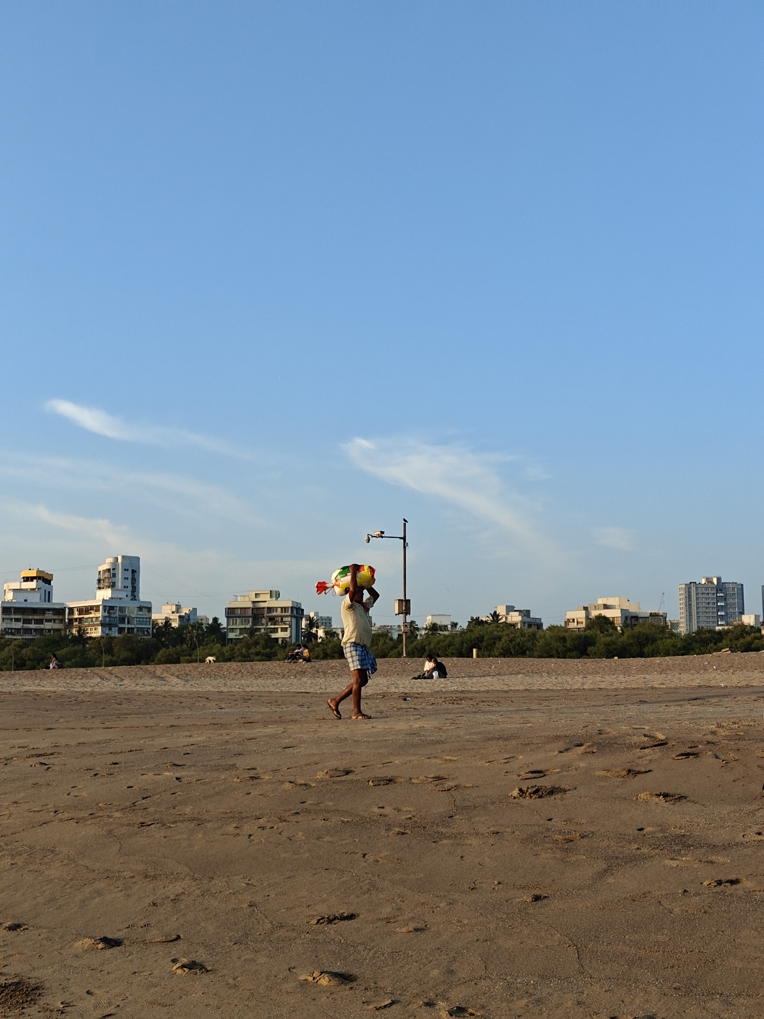 Beach vendors carry goods along Mumbai shoreline