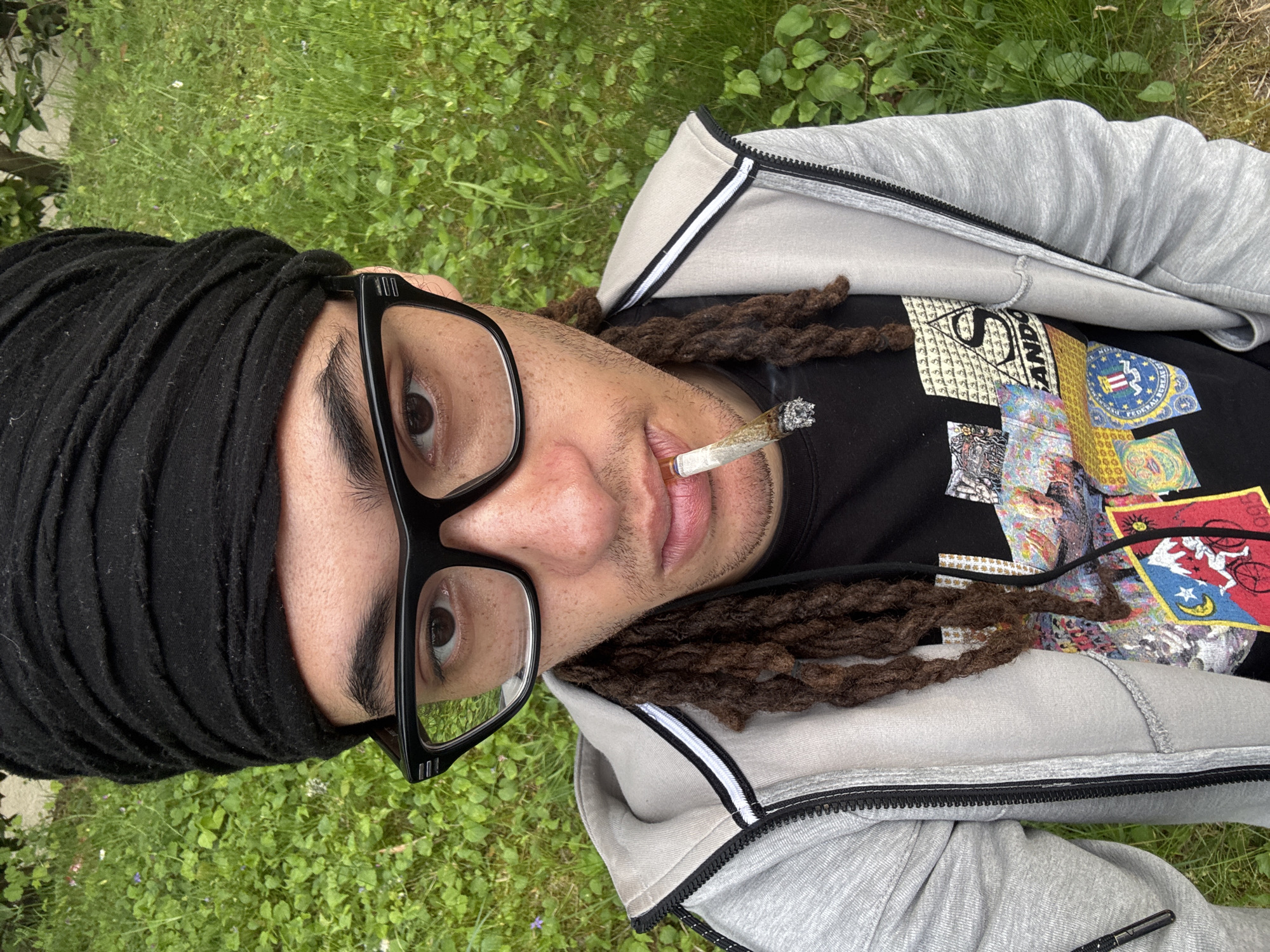 Person smoking cannabis while lying on grass in Les Ulis