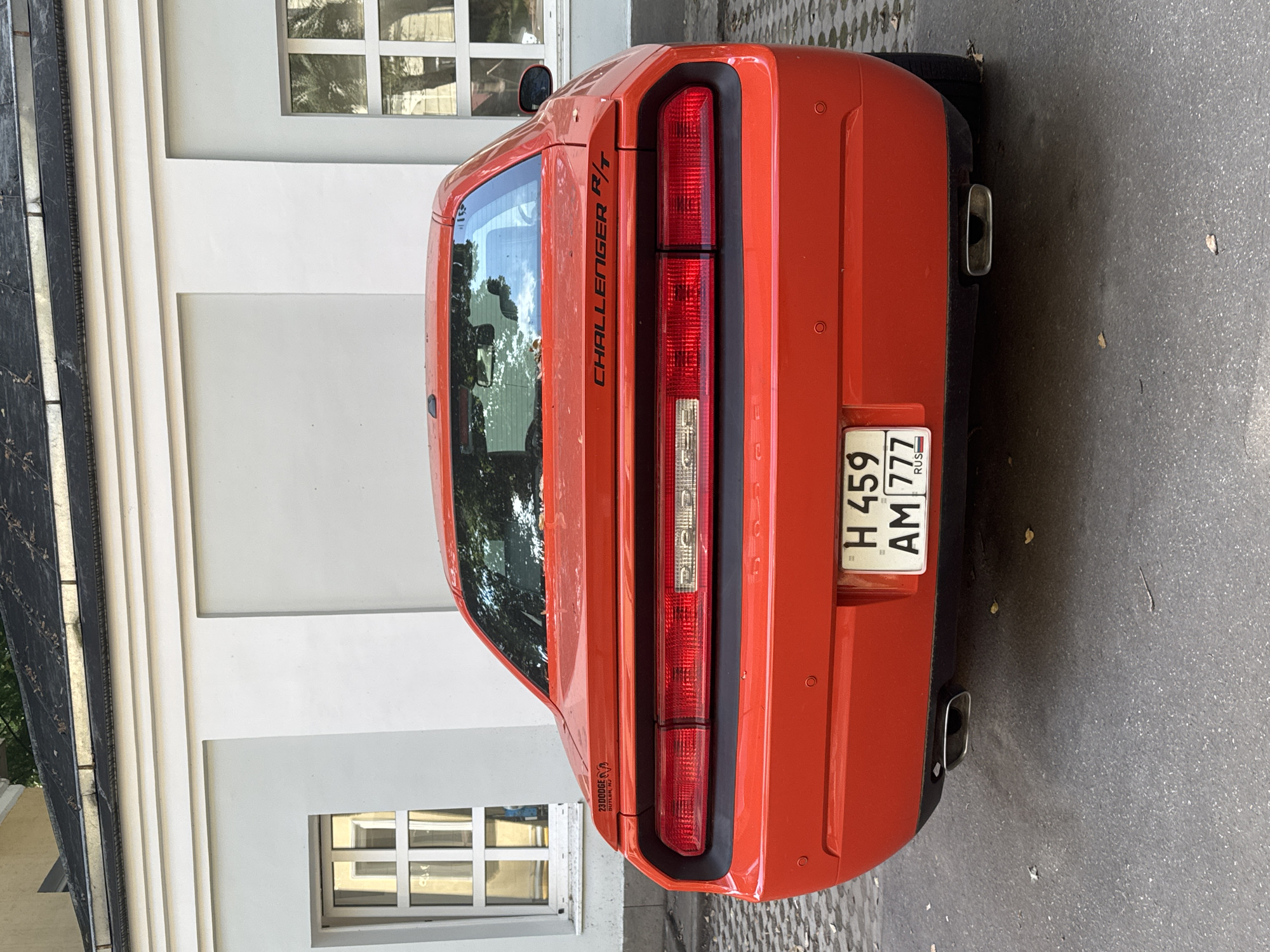 Red Dodge Challenger R/T parked near Moscow landmark, Sheltie in tow