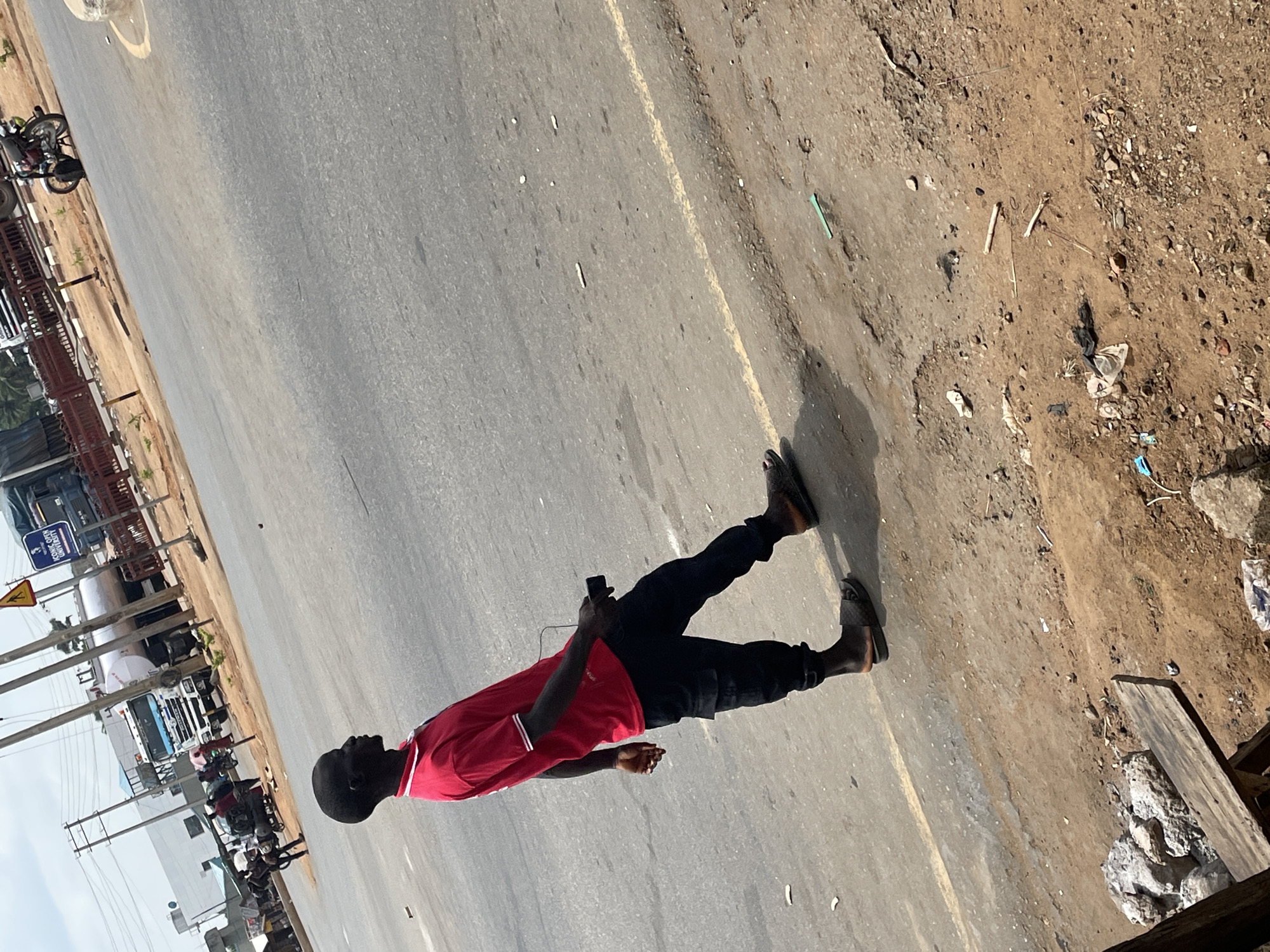 Man walks roadside with phone in Akwanga, Nigeria