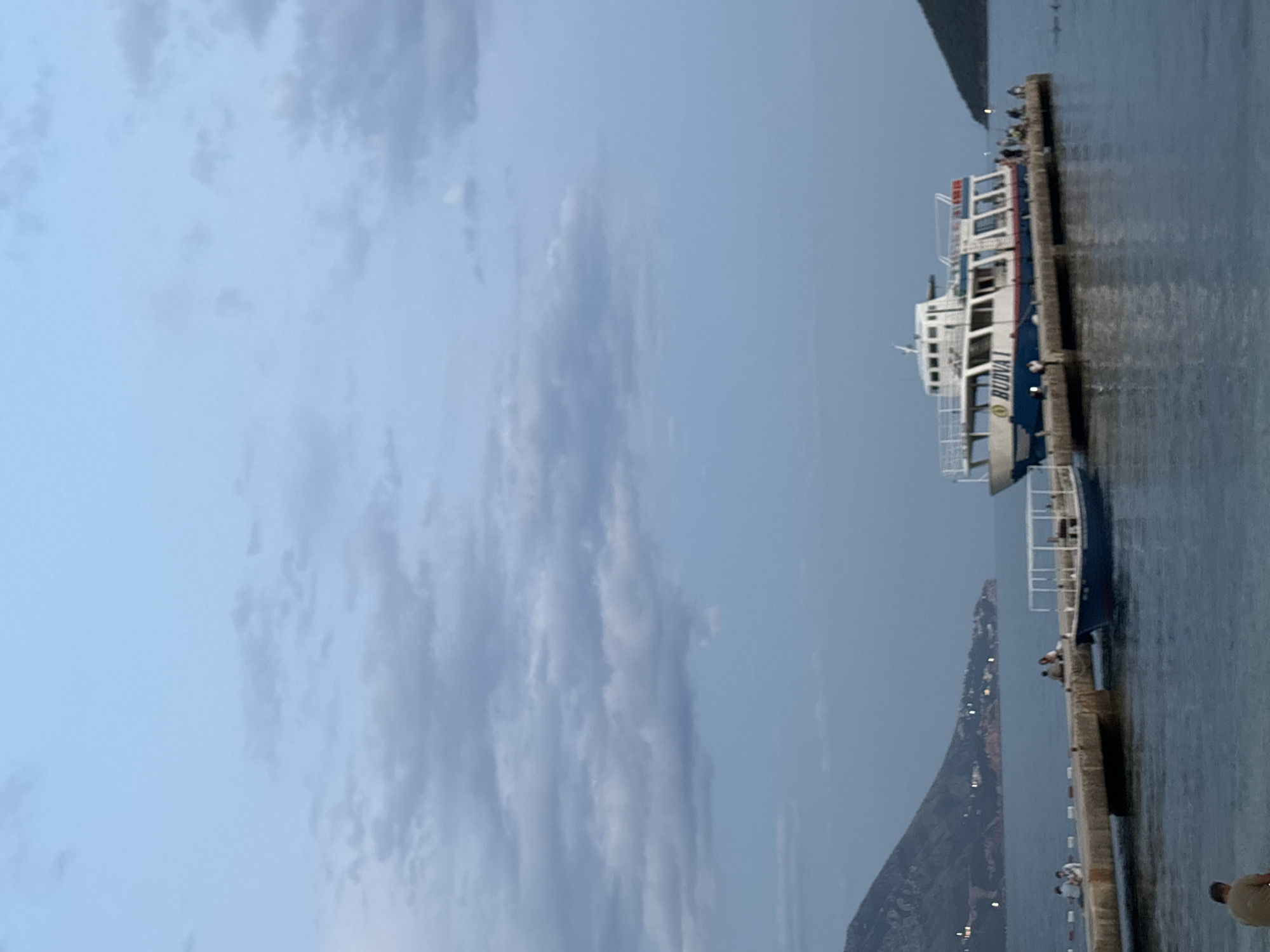Budva waterfront at dusk: ferry docked, kayaks on the beach