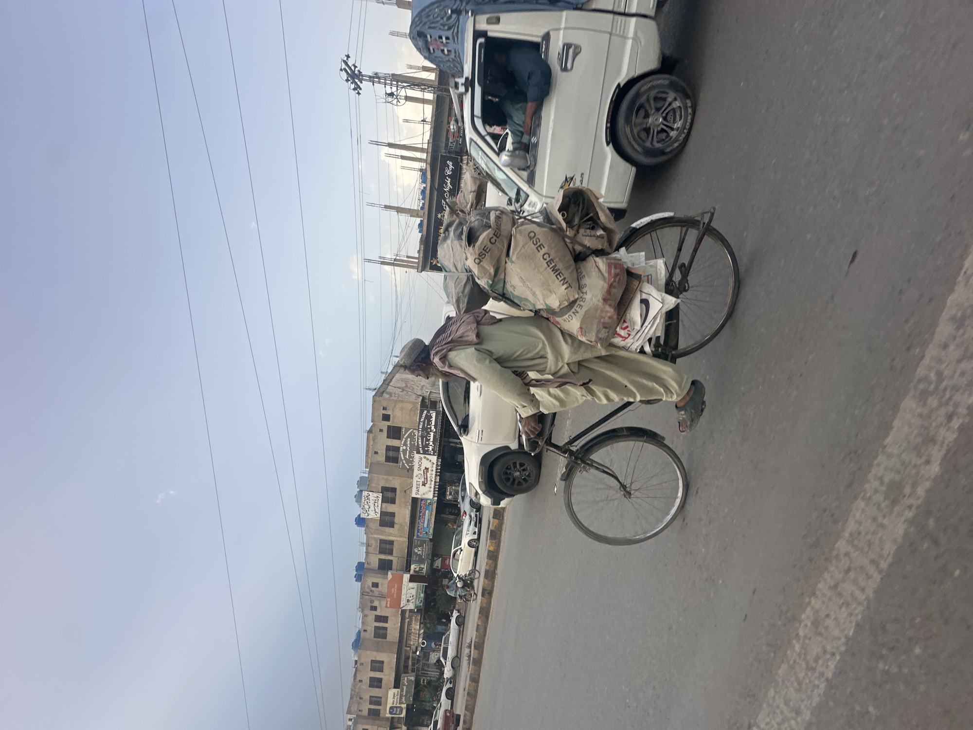 Cyclist transports cement bags on overloaded bicycle in Quetta