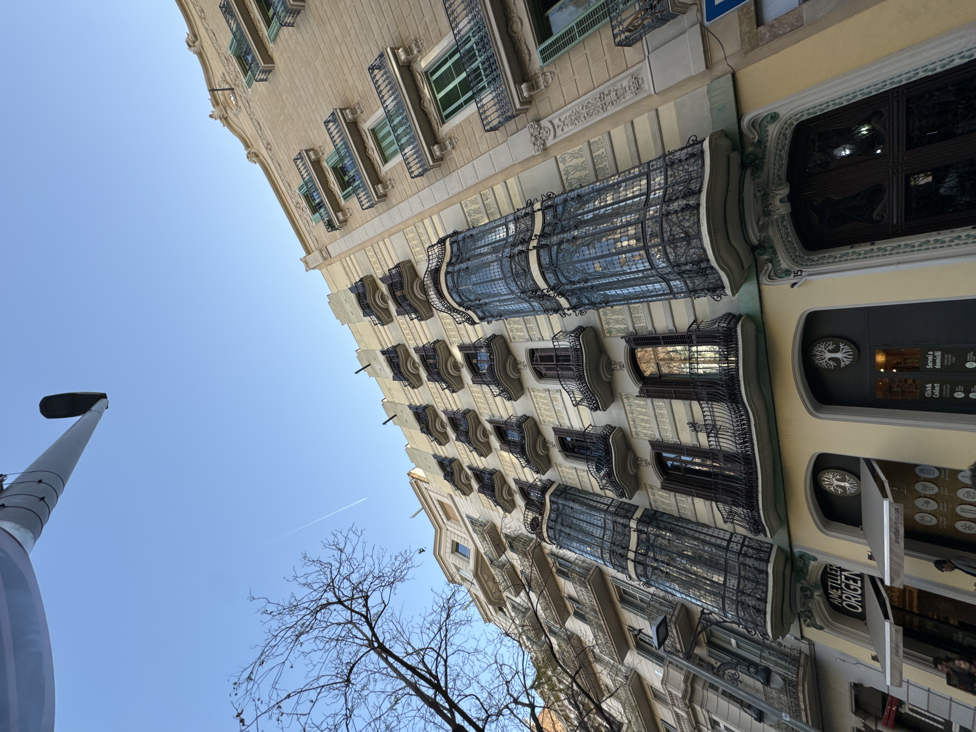 Cyclist rides red bike past ornate Barcelona buildings