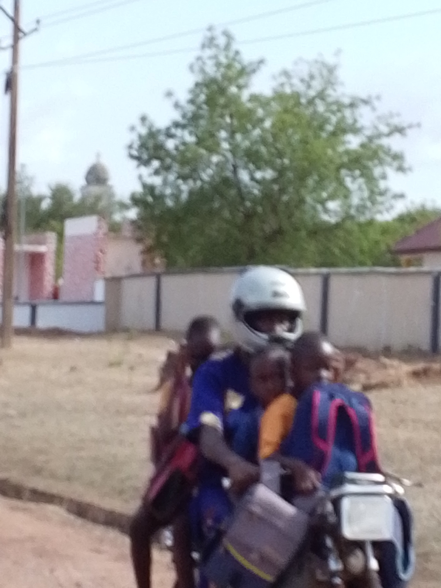 Motorcycle carries multiple children through dusty Tamale streets