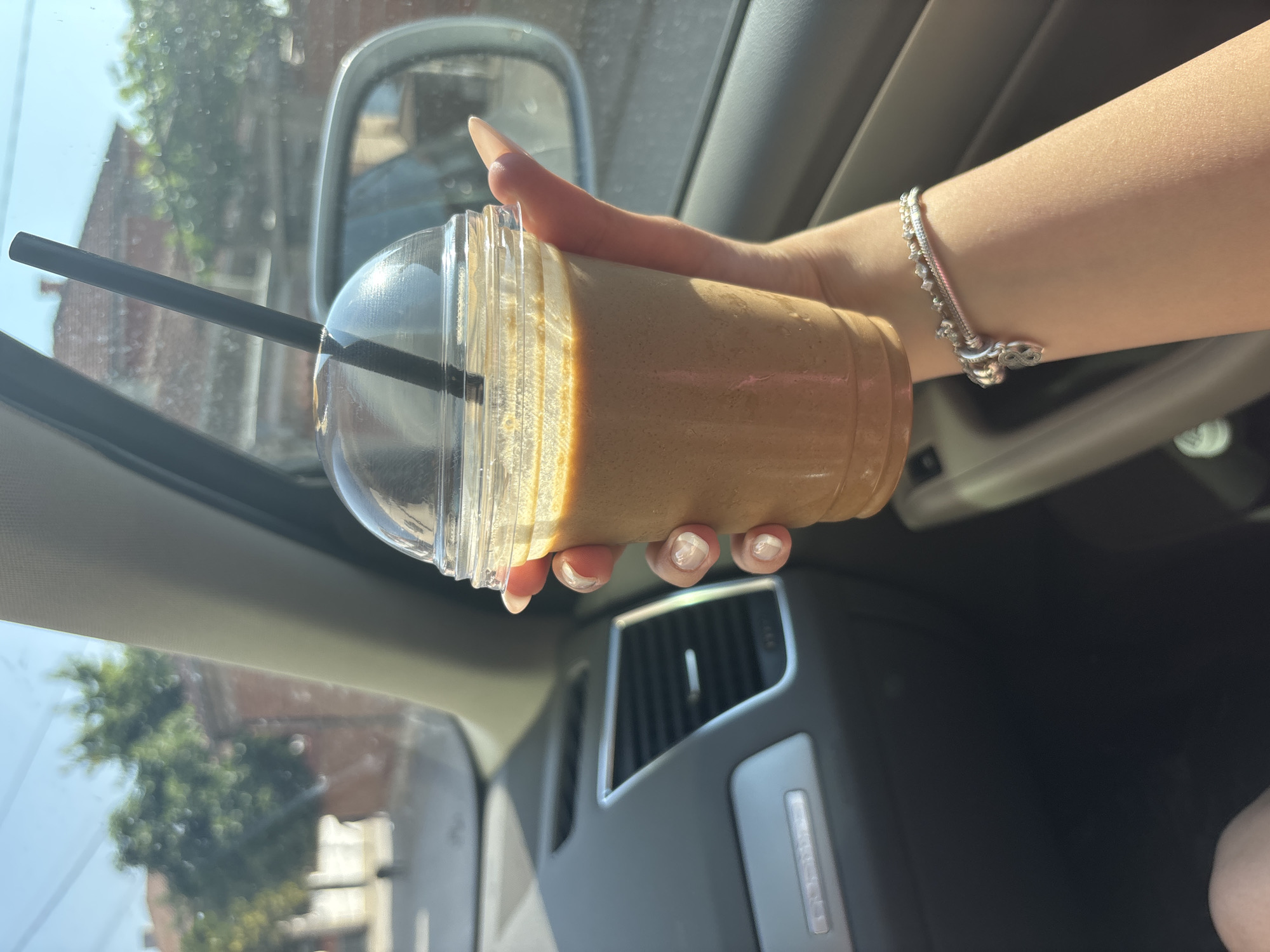 Woman enjoys iced coffee in car on sunny Rakovski afternoon
