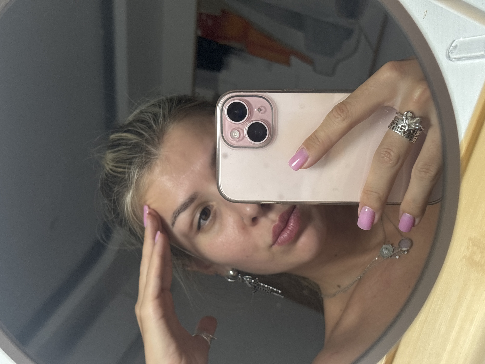 Mirror selfie session with a pink iPhone, round mirror
