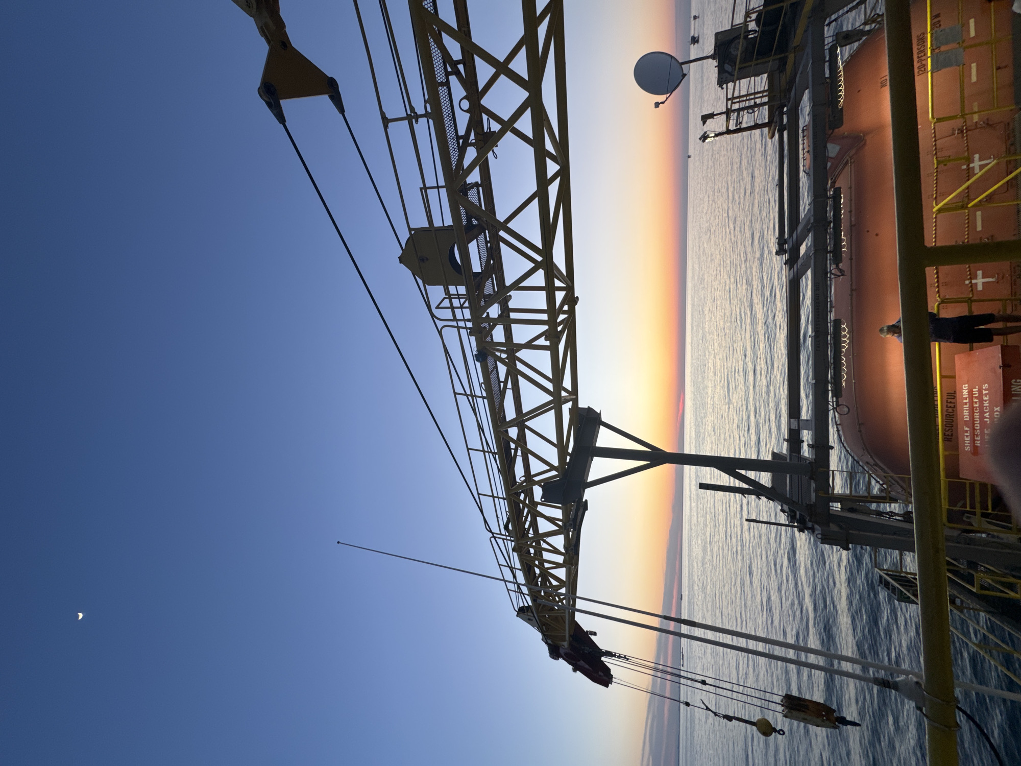 Yellow offshore crane observed during sunset near Italian coast