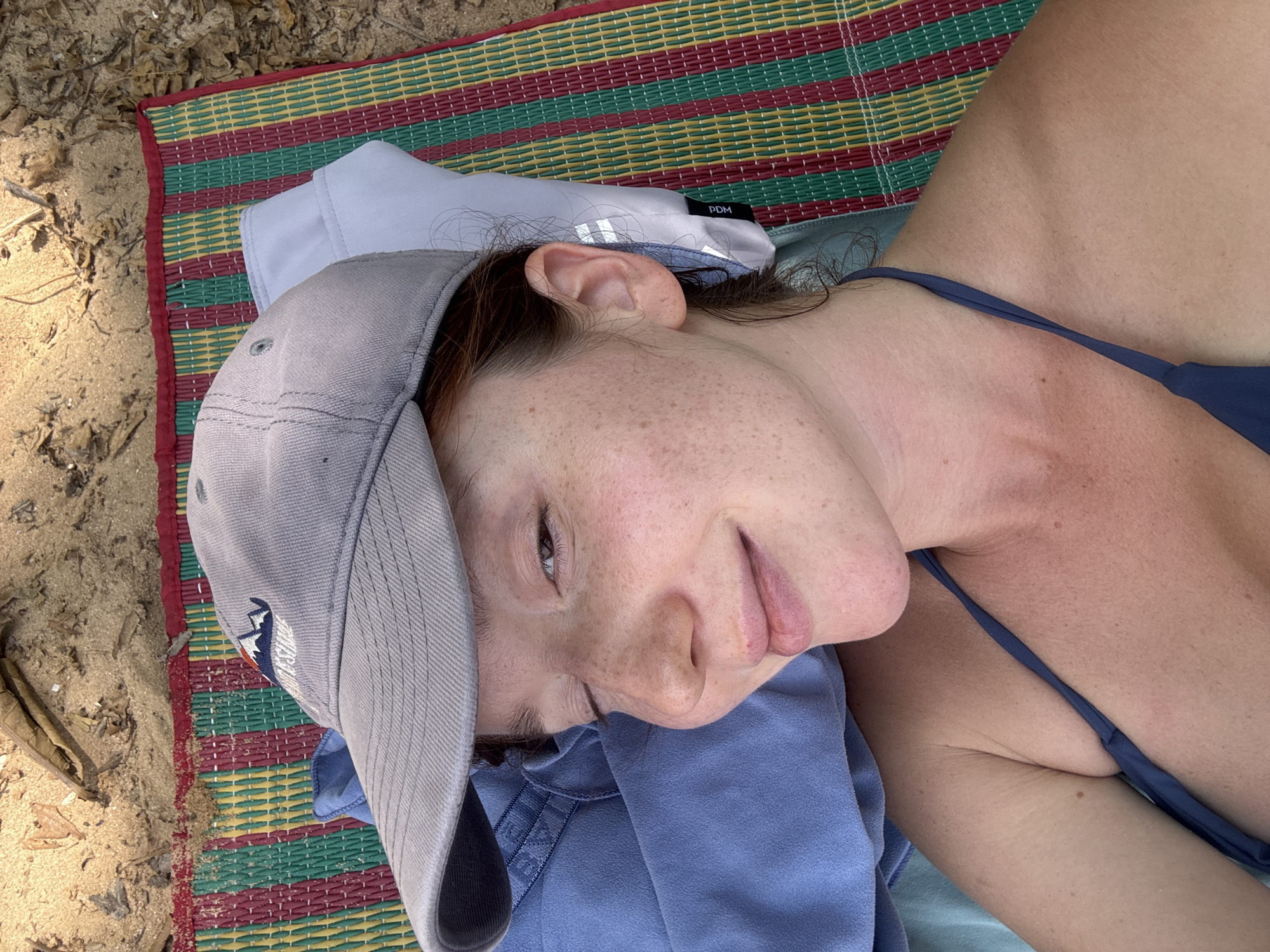 Woman relaxes on beach mat in early morning Thailand