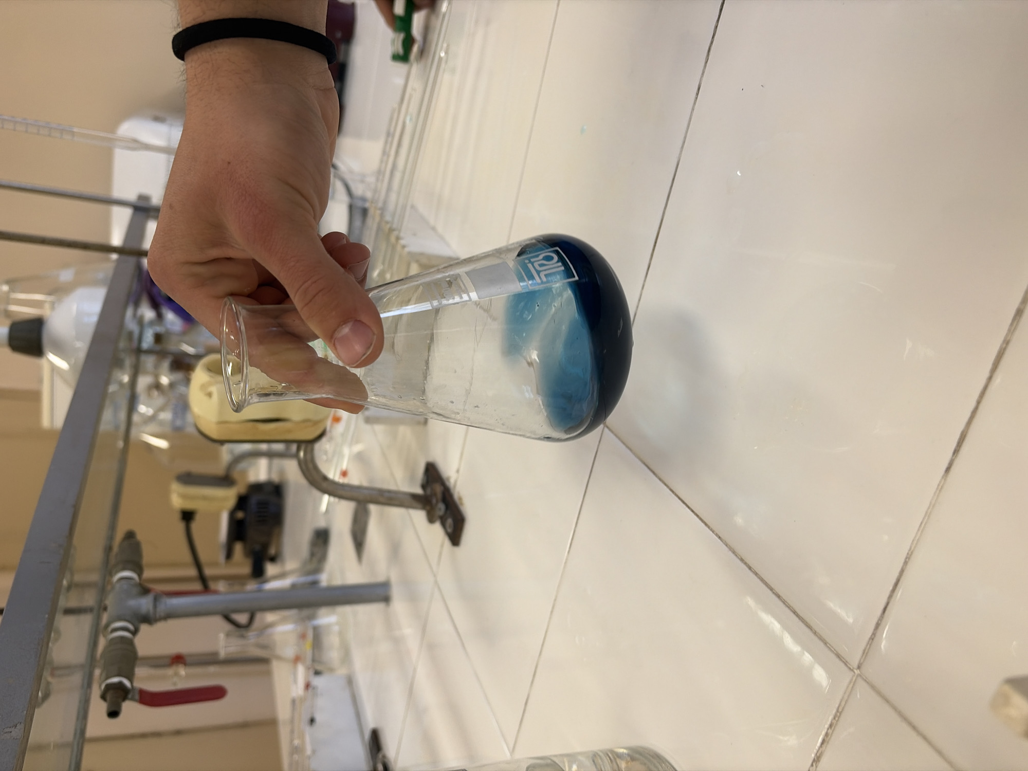 Person handles blue liquid in laboratory flask