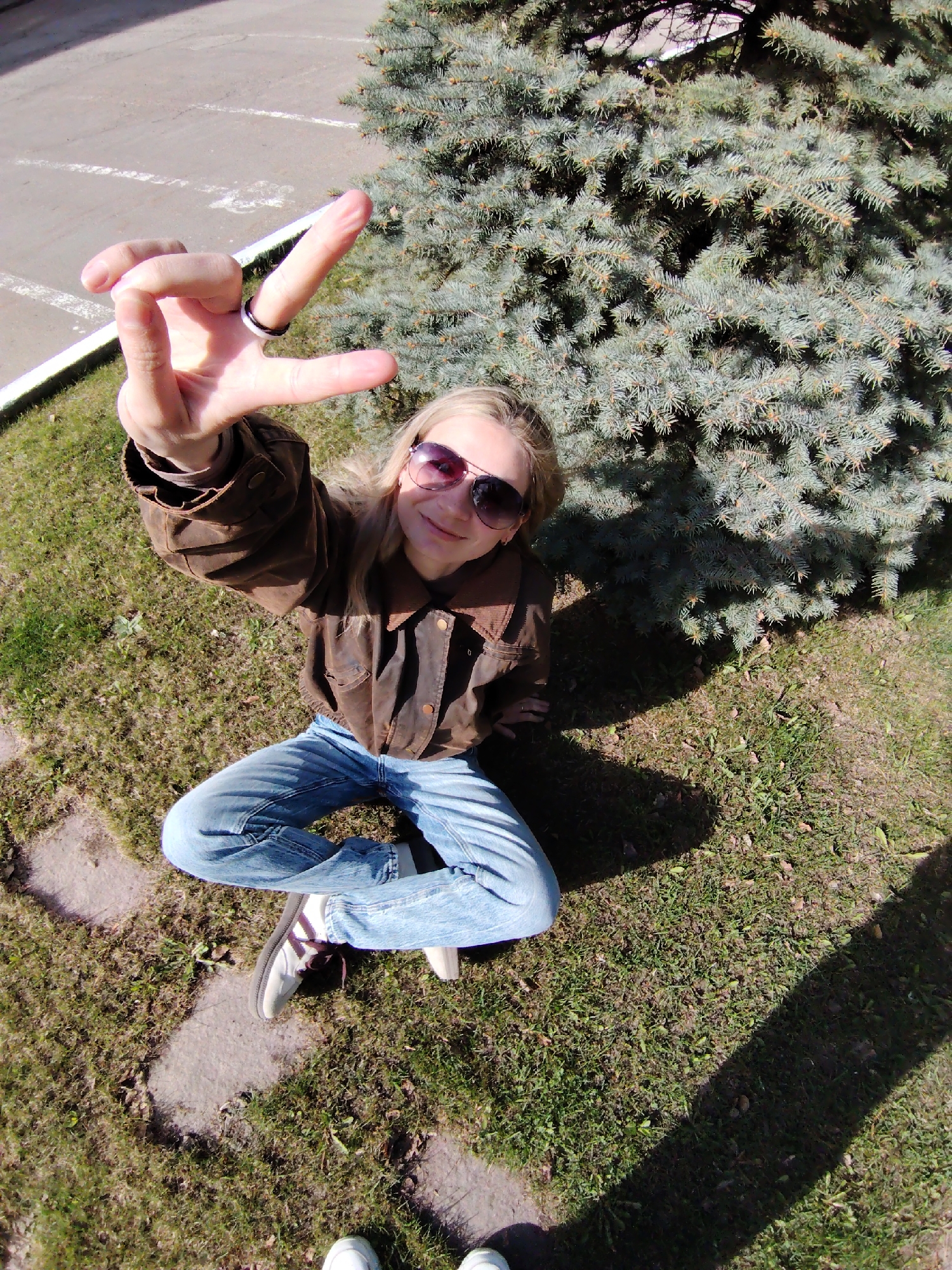 Person makes peace sign while sitting outdoors in Chaikovsky
