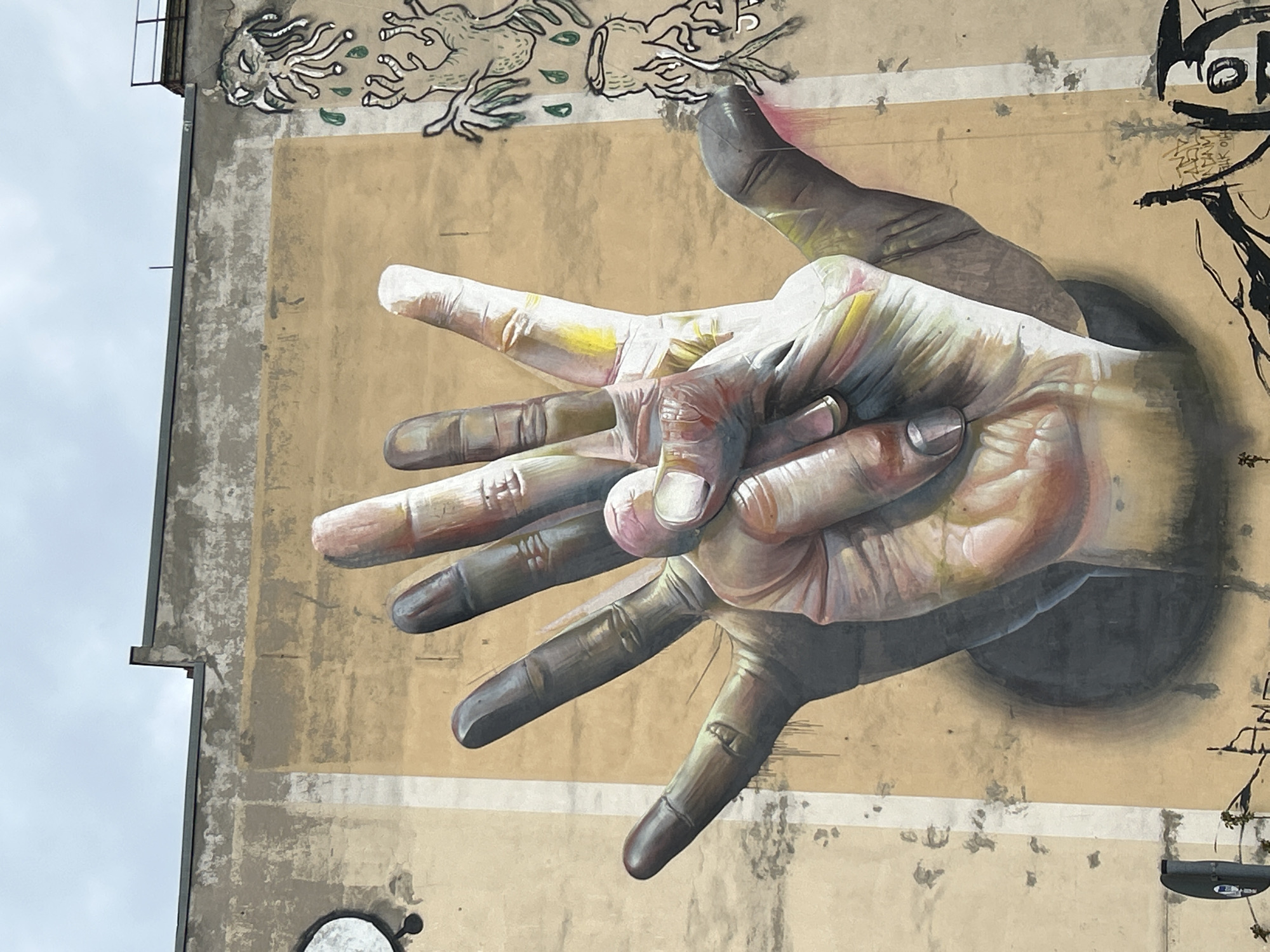 Berlin street art featuring photorealistic hands mural documented