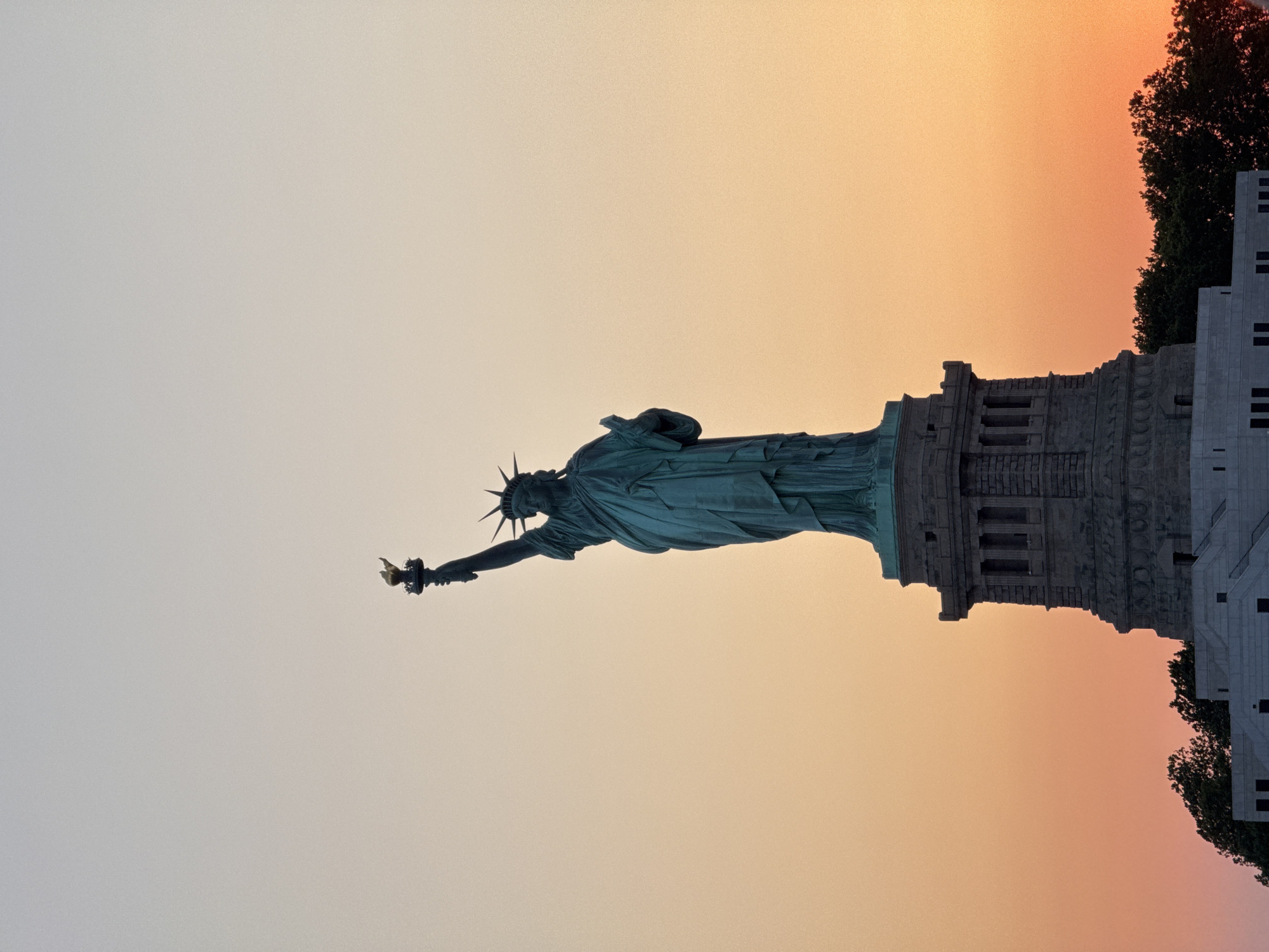 Statue of Liberty silhouetted at dusk over New York Harbor