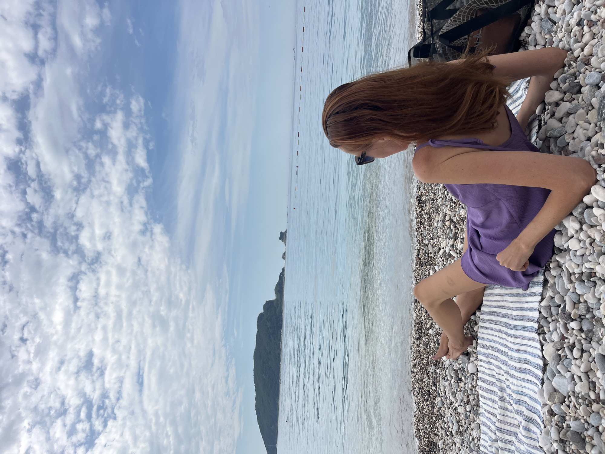Woman in purple dress enjoys morning beach time in Budva