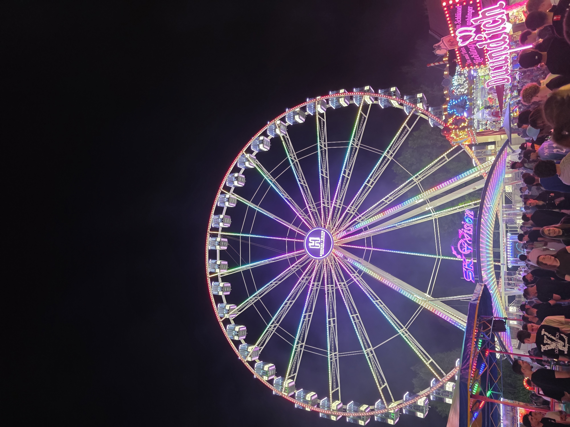 Rainbow-lit Ferris wheel with 'H' symbol draws crowds in Salzburg