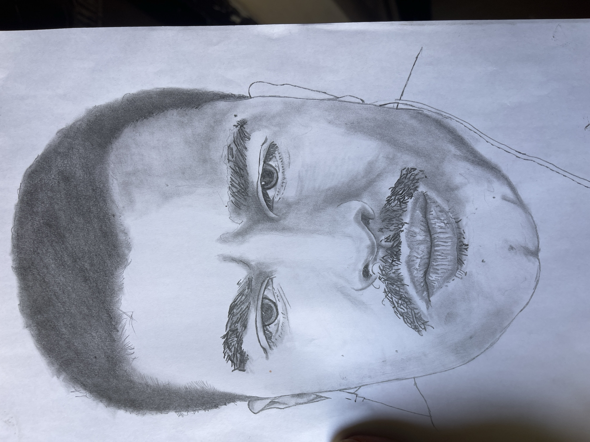 Artist creates pencil portrait from laptop reference in Jos