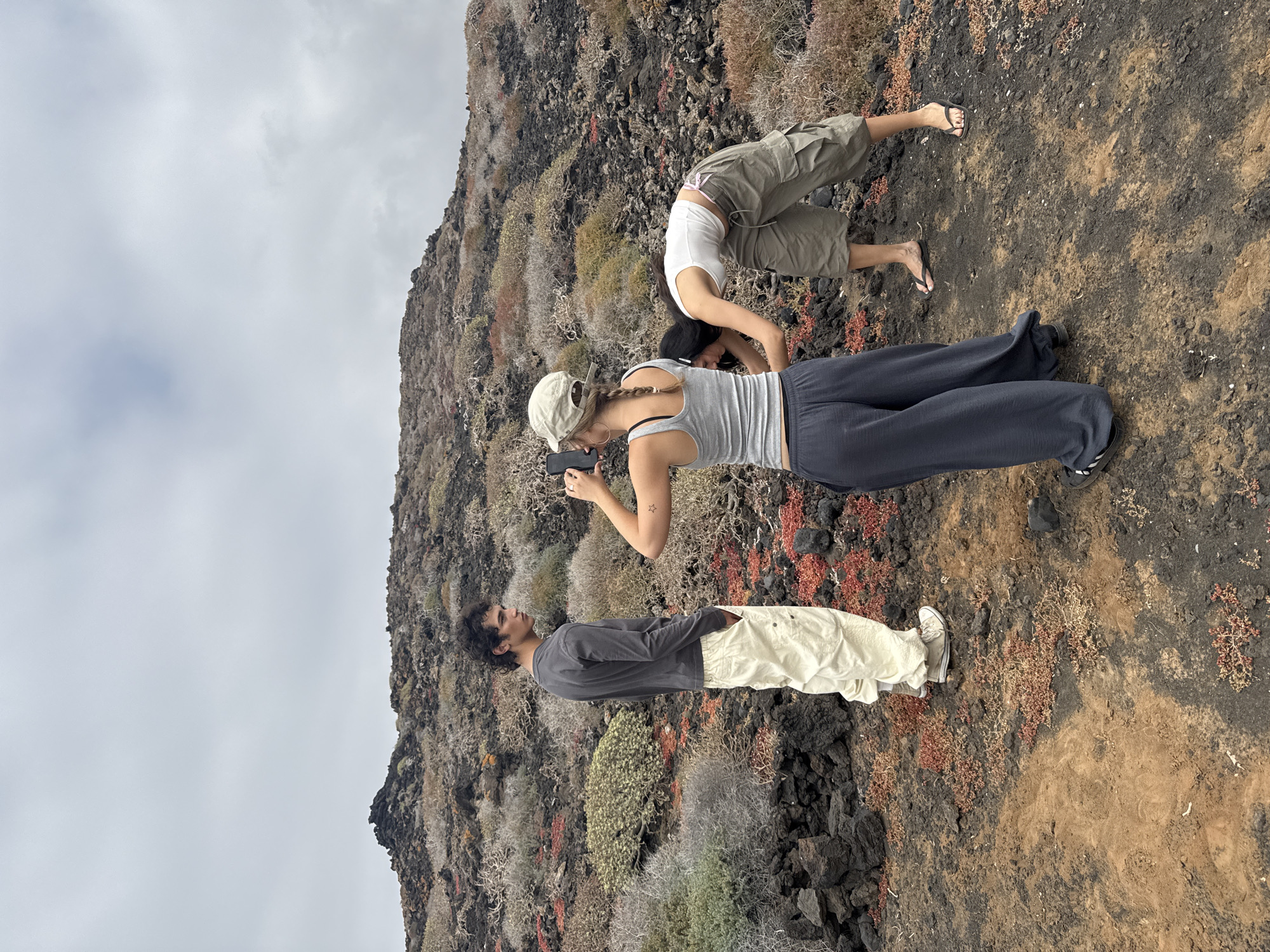 Three people gather on volcanic terrain in Tinajo