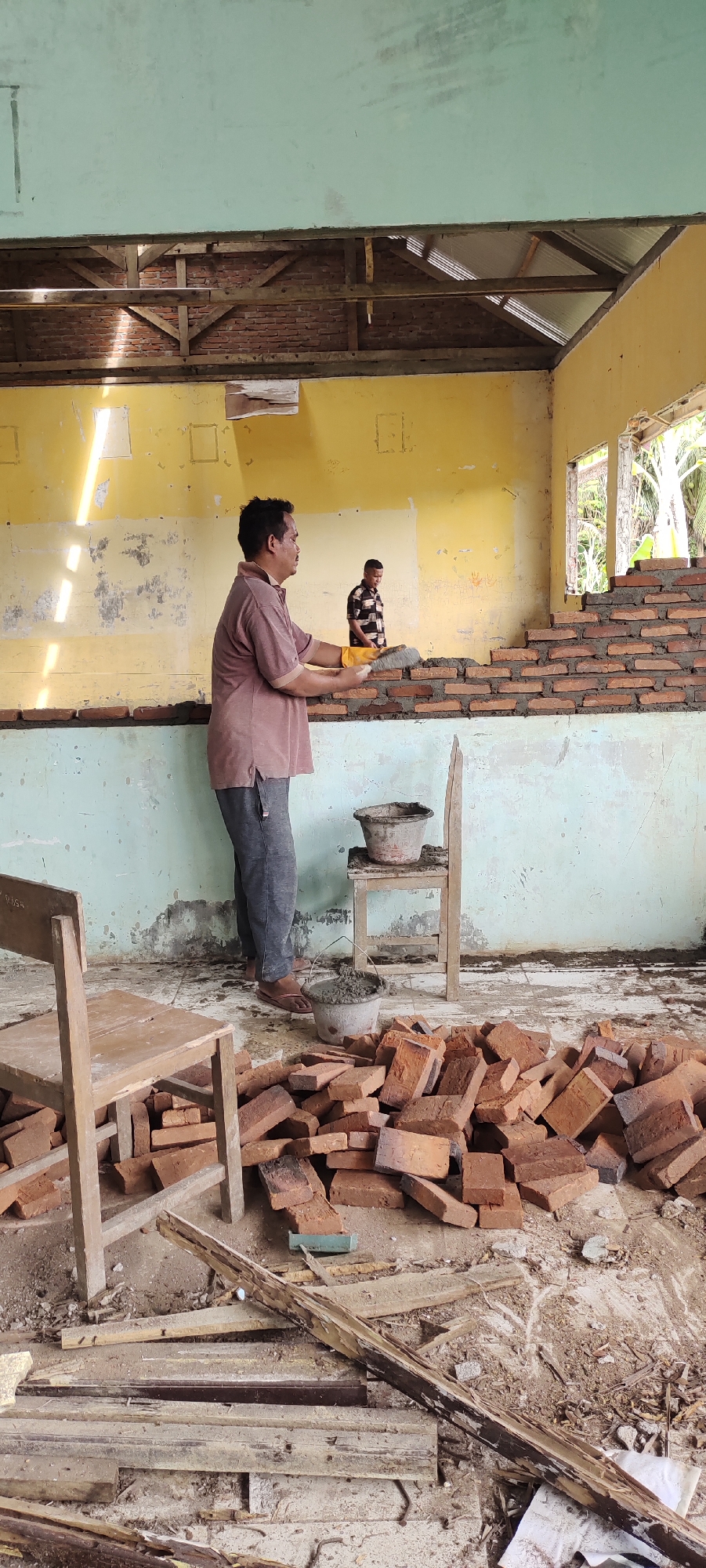 Construction workers lay bricks in deteriorated Langnibong building