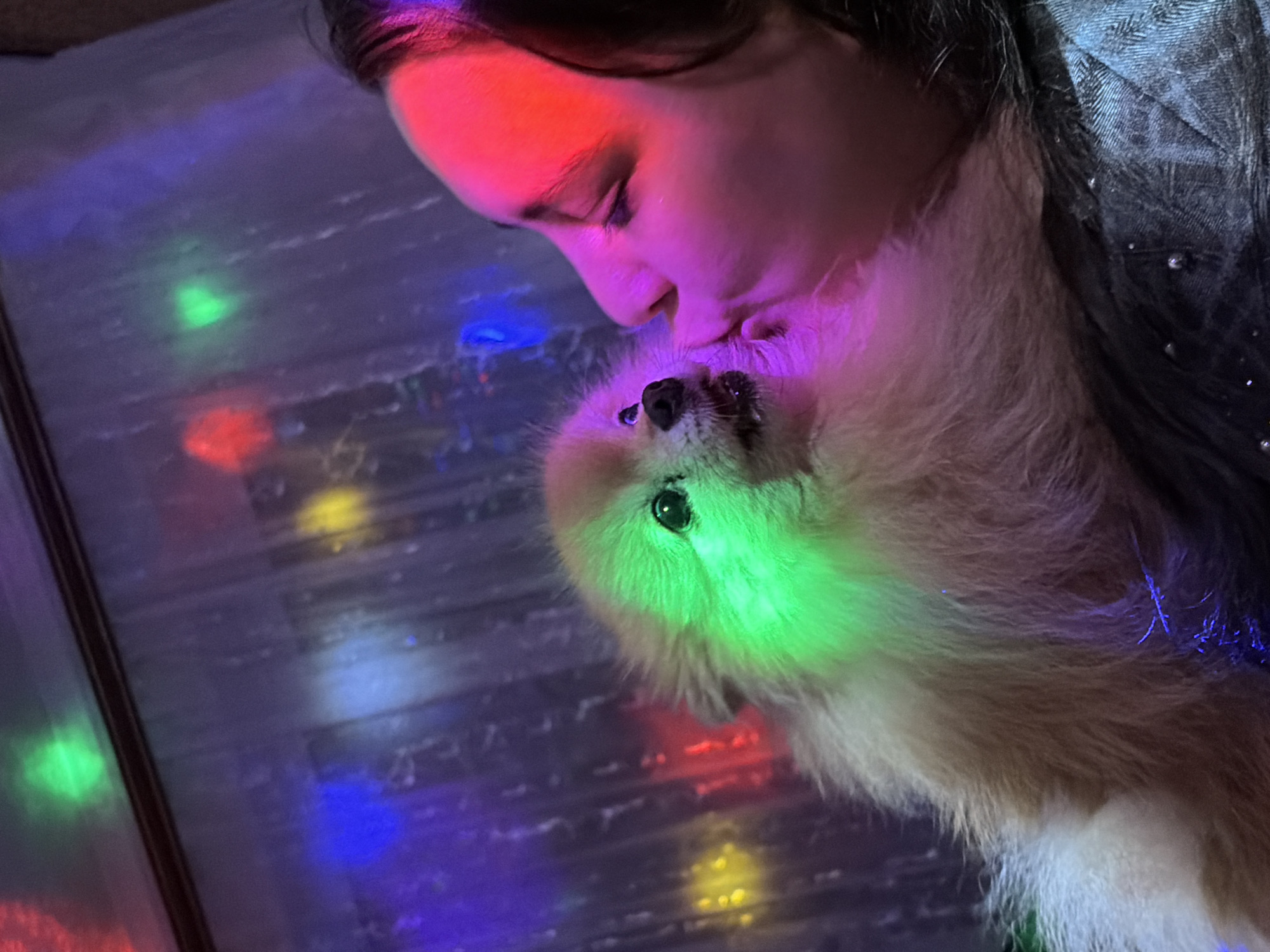 Woman spends evening with Pomeranian dog in colorful indoor setting
