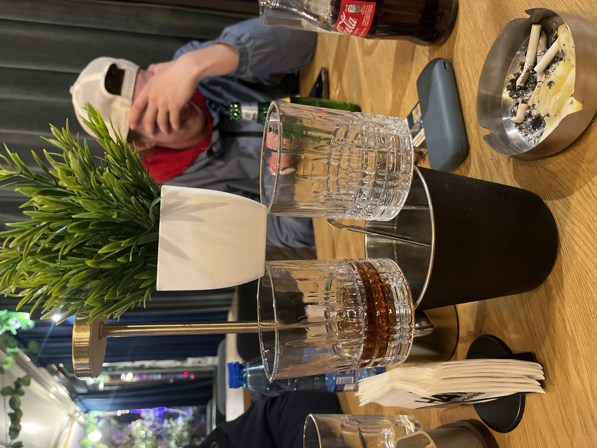 Person in white cap at Sofia bar table with green bottle