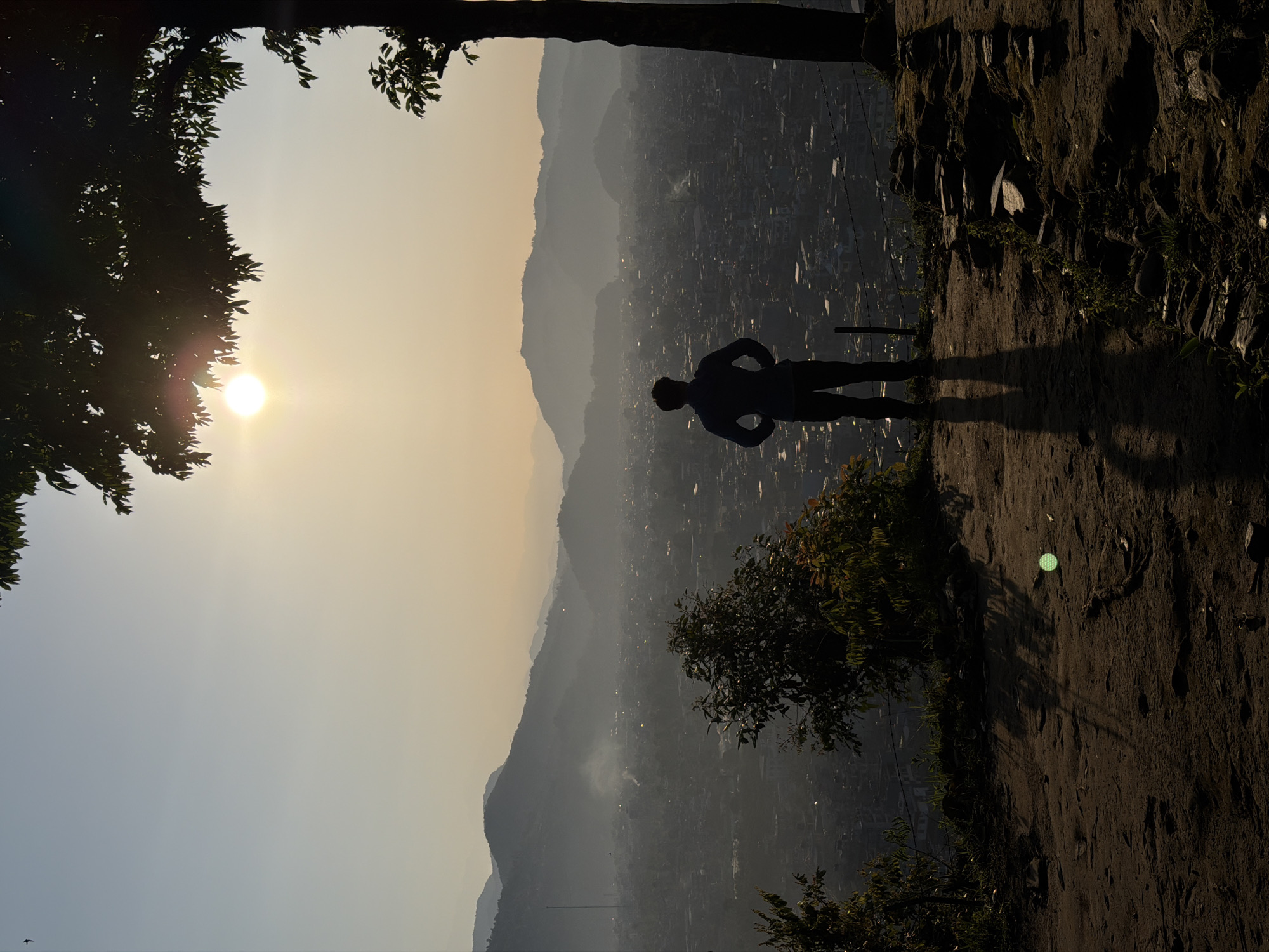 Person stands on cliff edge during sunrise in Pokhara