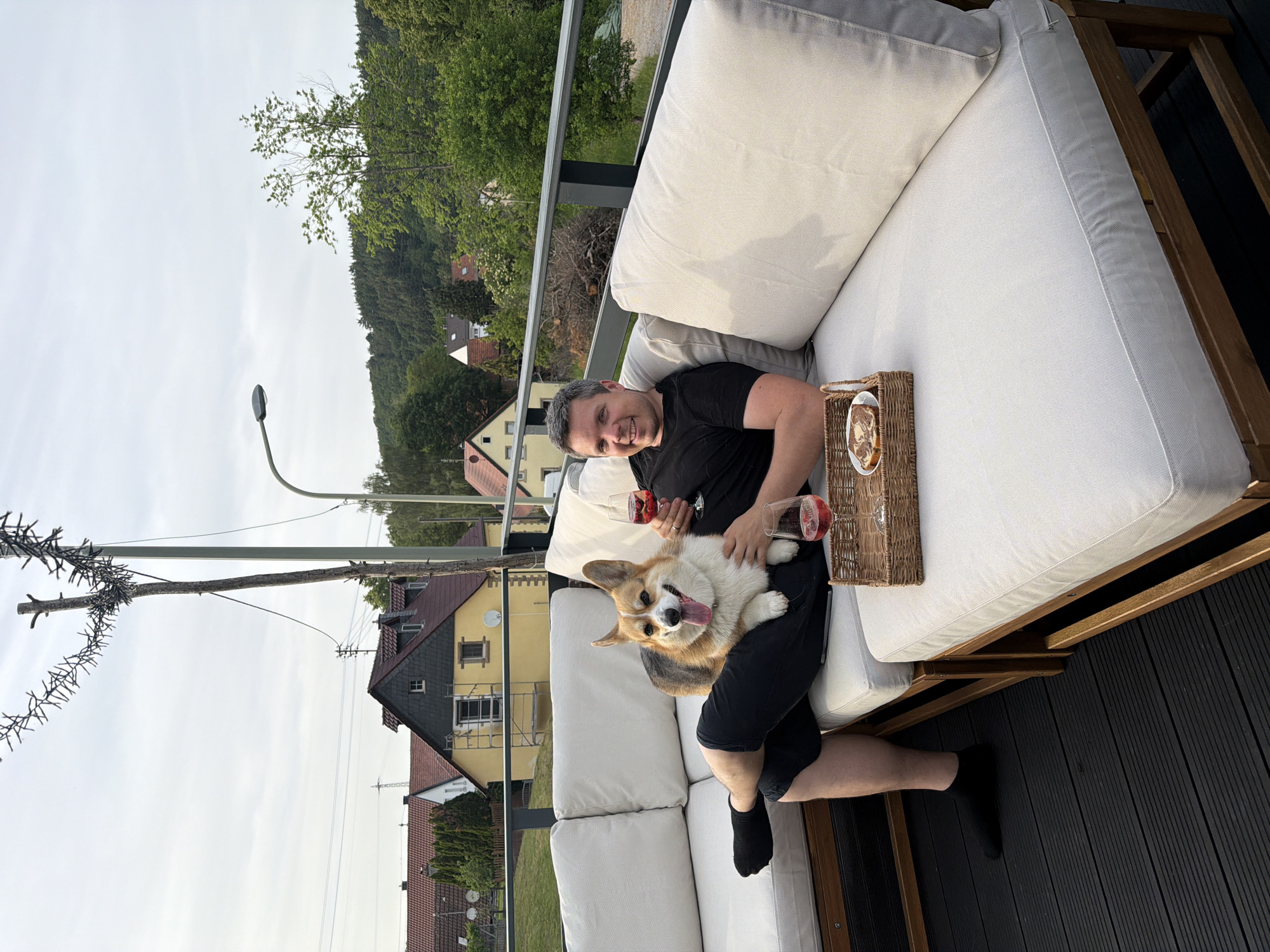 Man relaxes with corgi and wine on German terrace