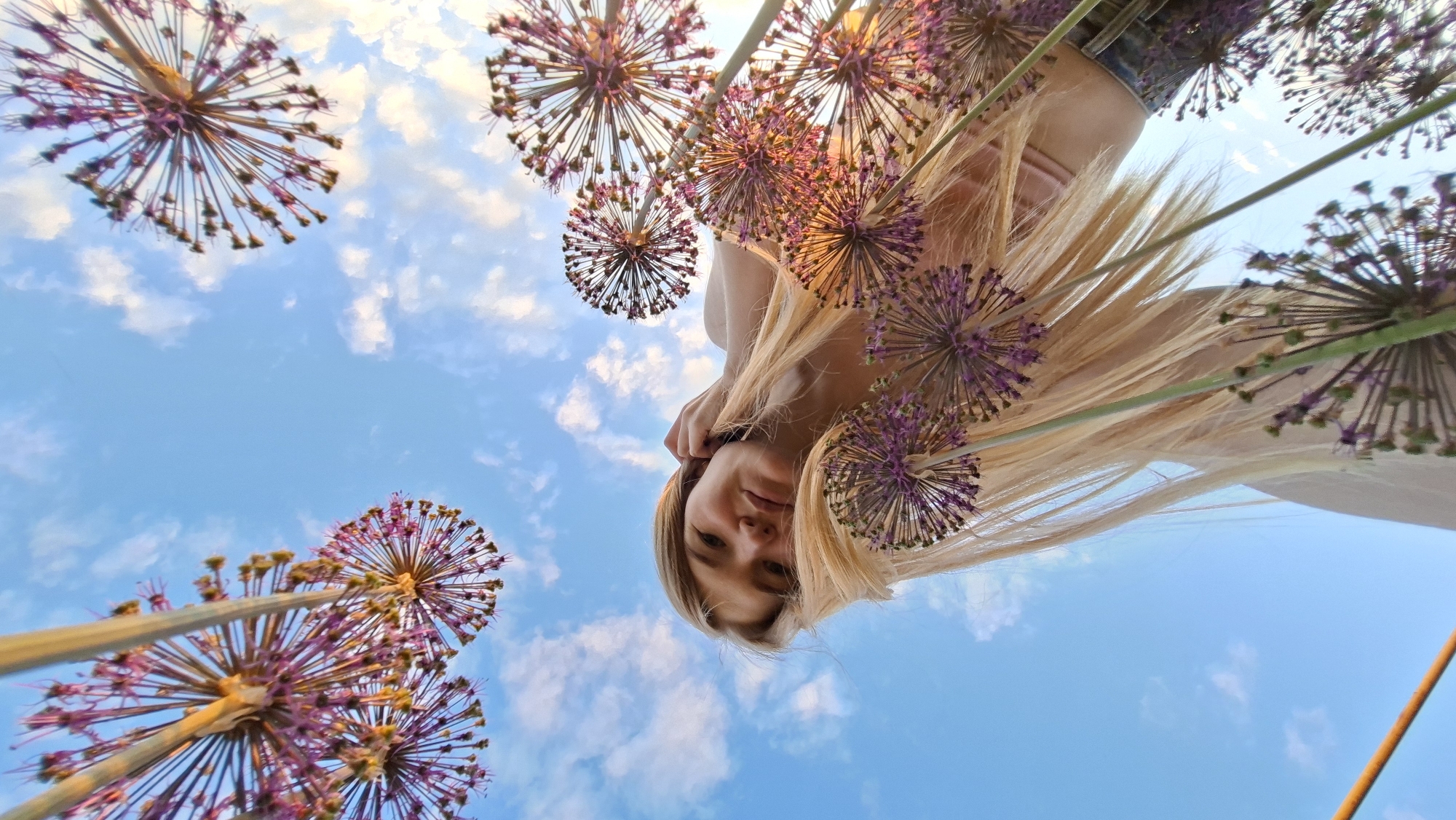 Woman photographs herself among purple flowers in Russian garden
